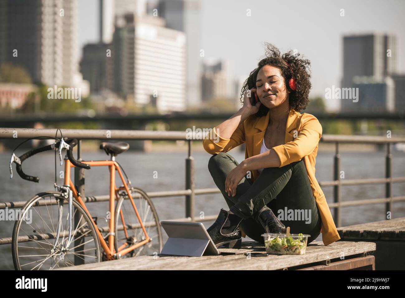 Geschäftsfrau, die an sonnigen Tagen Musik am Main hört Stockfoto