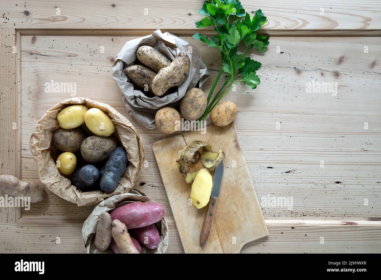 Petersilie und verschiedene Sorten von Rohkartoffeln auf rustikalem Holzhintergrund Stockfoto