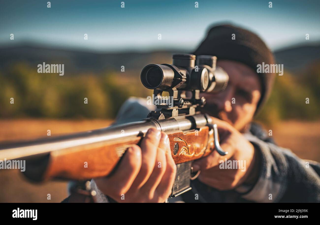 Jäger mit kraftvollem Gewehr mit Zielfernrohr Tiere zu beobachten. Jäger mit Schrotflinte auf der Jagd. Hunter in der Herbstjagd Saison. Stockfoto