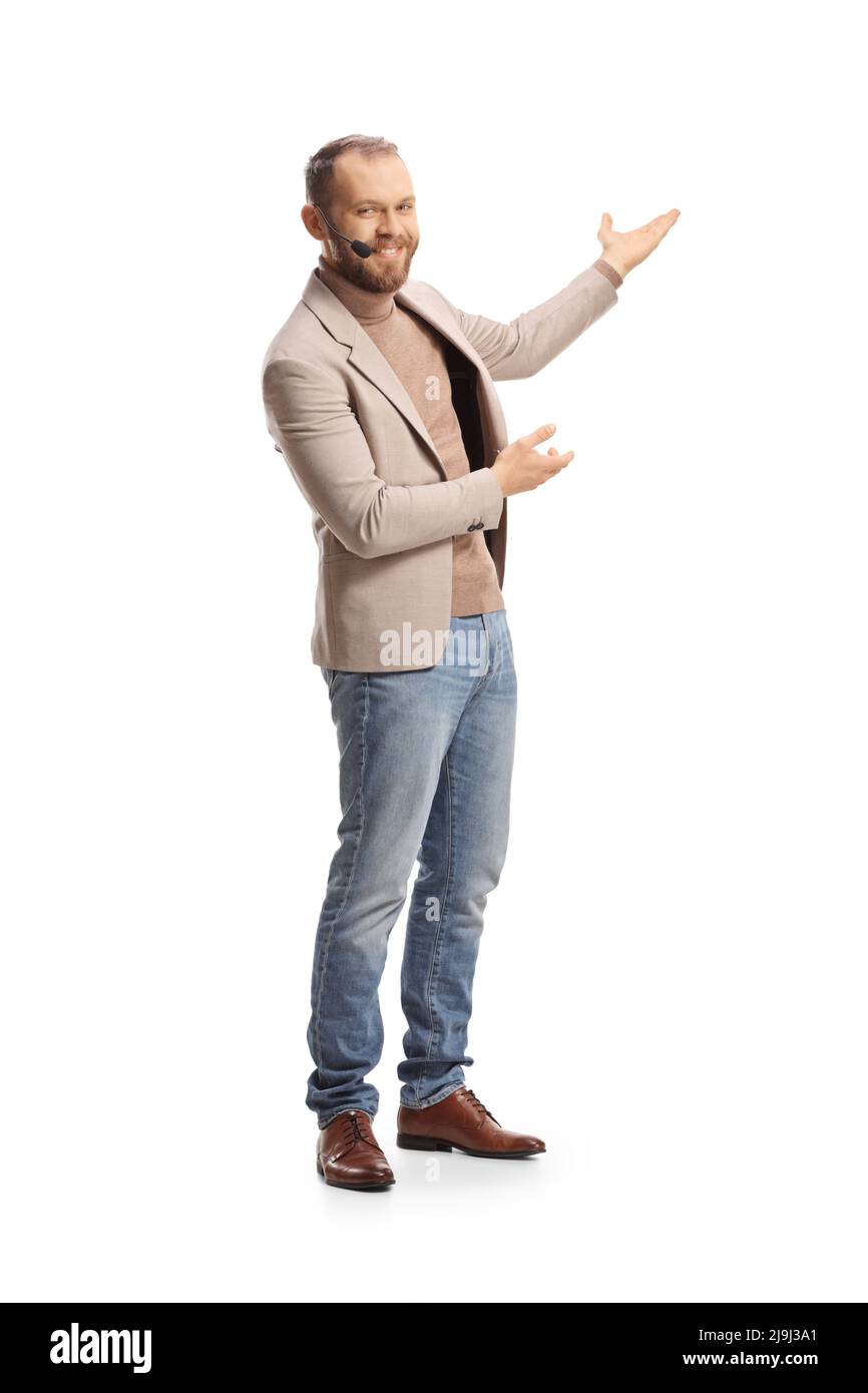 Ganzkörperaufnahme eines jungen Mannes mit einem Headset, das mit isolierten Händen auf weißem Hintergrund präsentiert Stockfoto