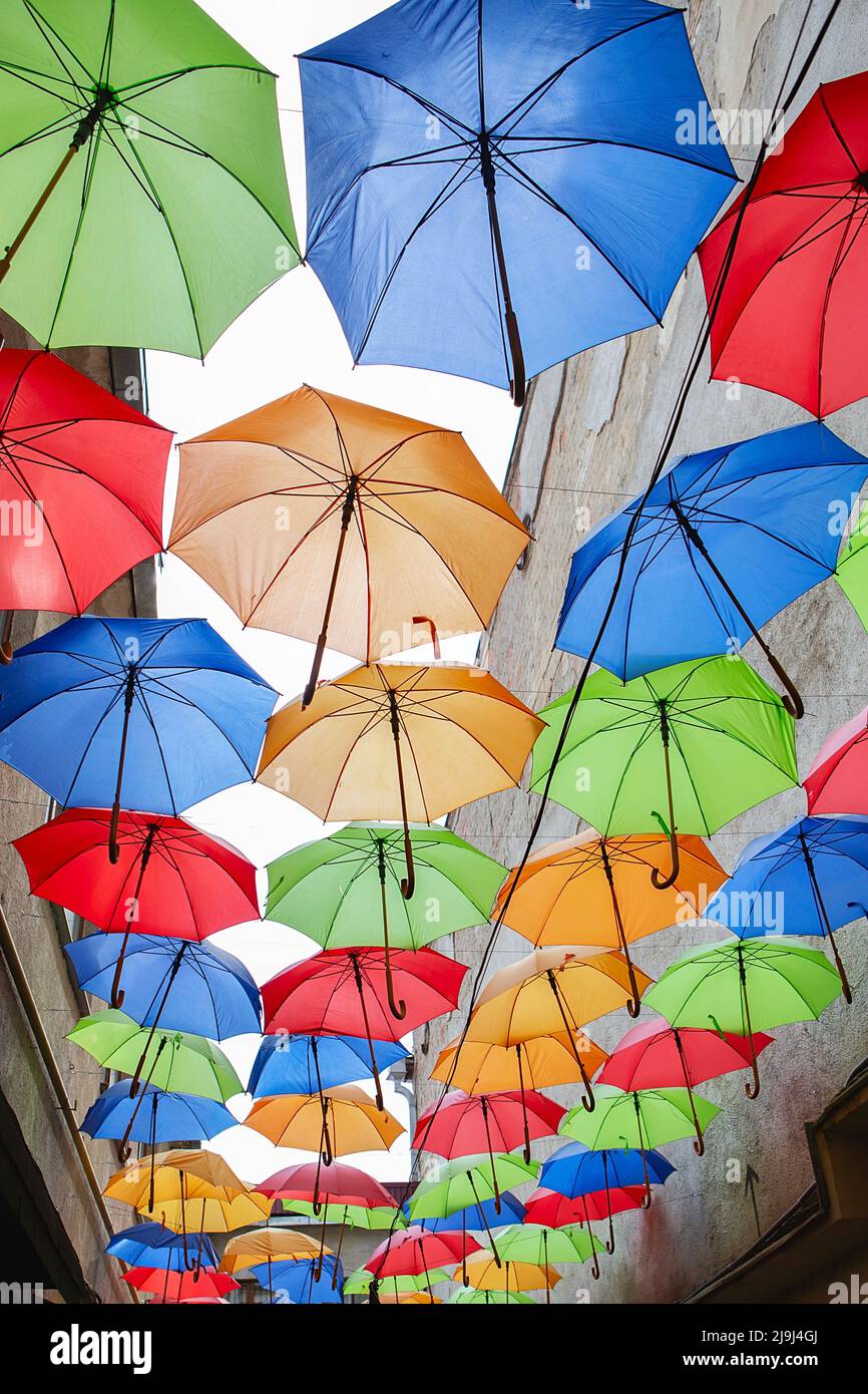 Regenschirme Ausstellung, Straße dekoriert. Der Himmel ist mit bunten Regenschirmen gefüllt. Viele bunte Regenschirme gegen den Himmel in Stadteinstellungen. Farbdruck Stockfoto
