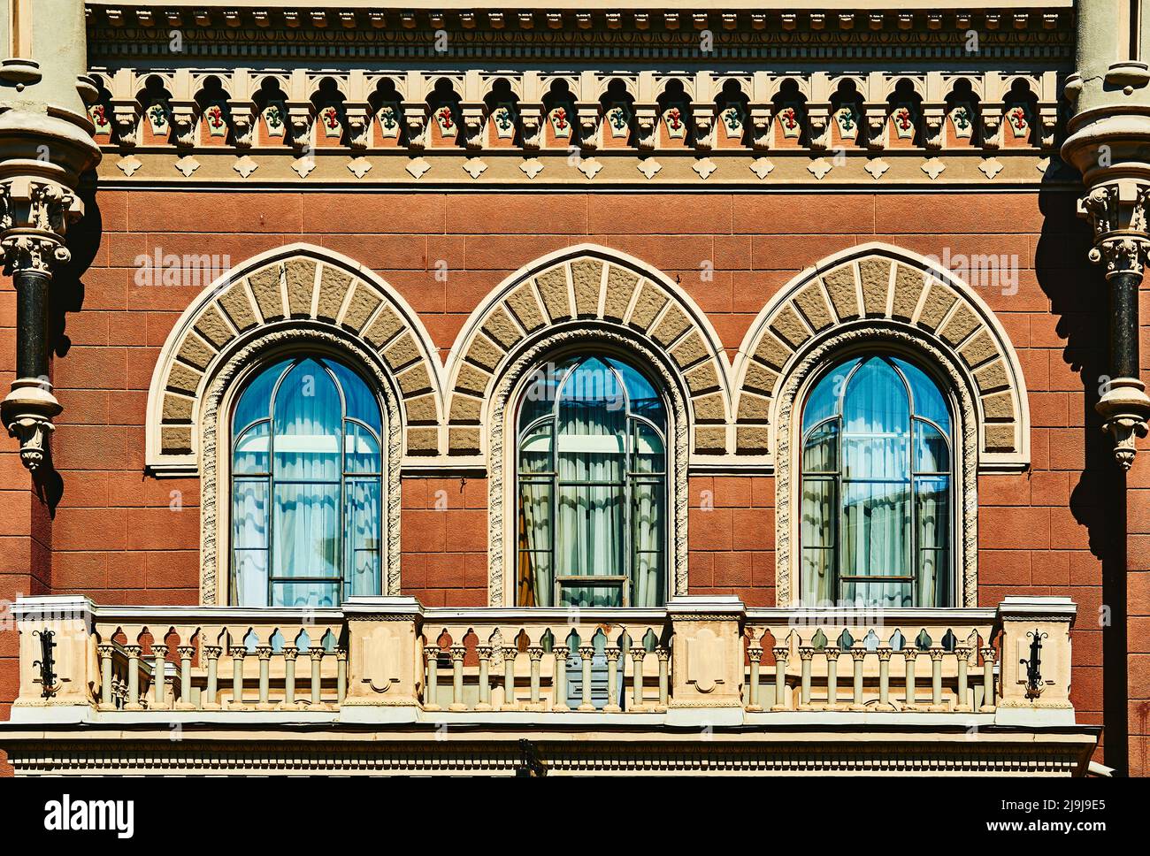 Fassade eines alten Gebäudes mit gotischen Fenstern und einem Balkon. Stockfoto