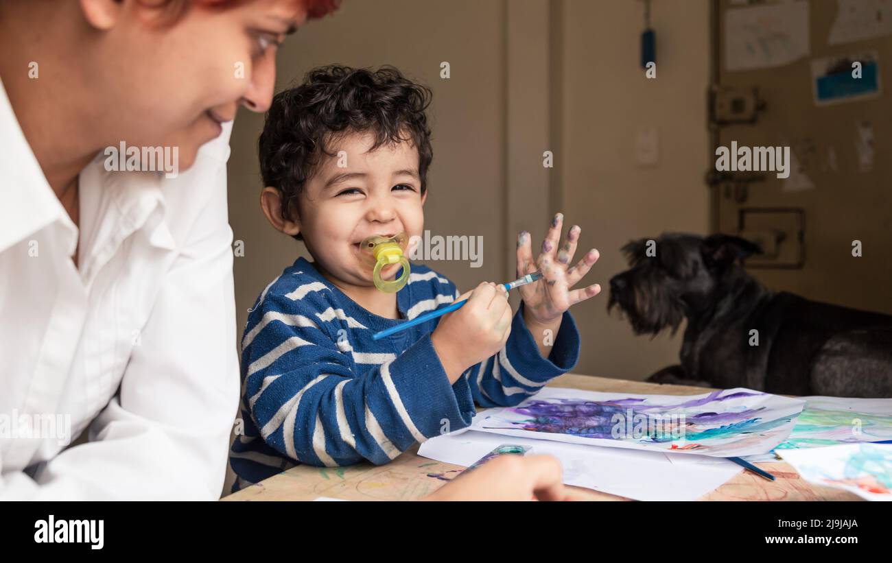 Lehrer, der einem Kind beibringt, mit Farben zu malen Stockfoto