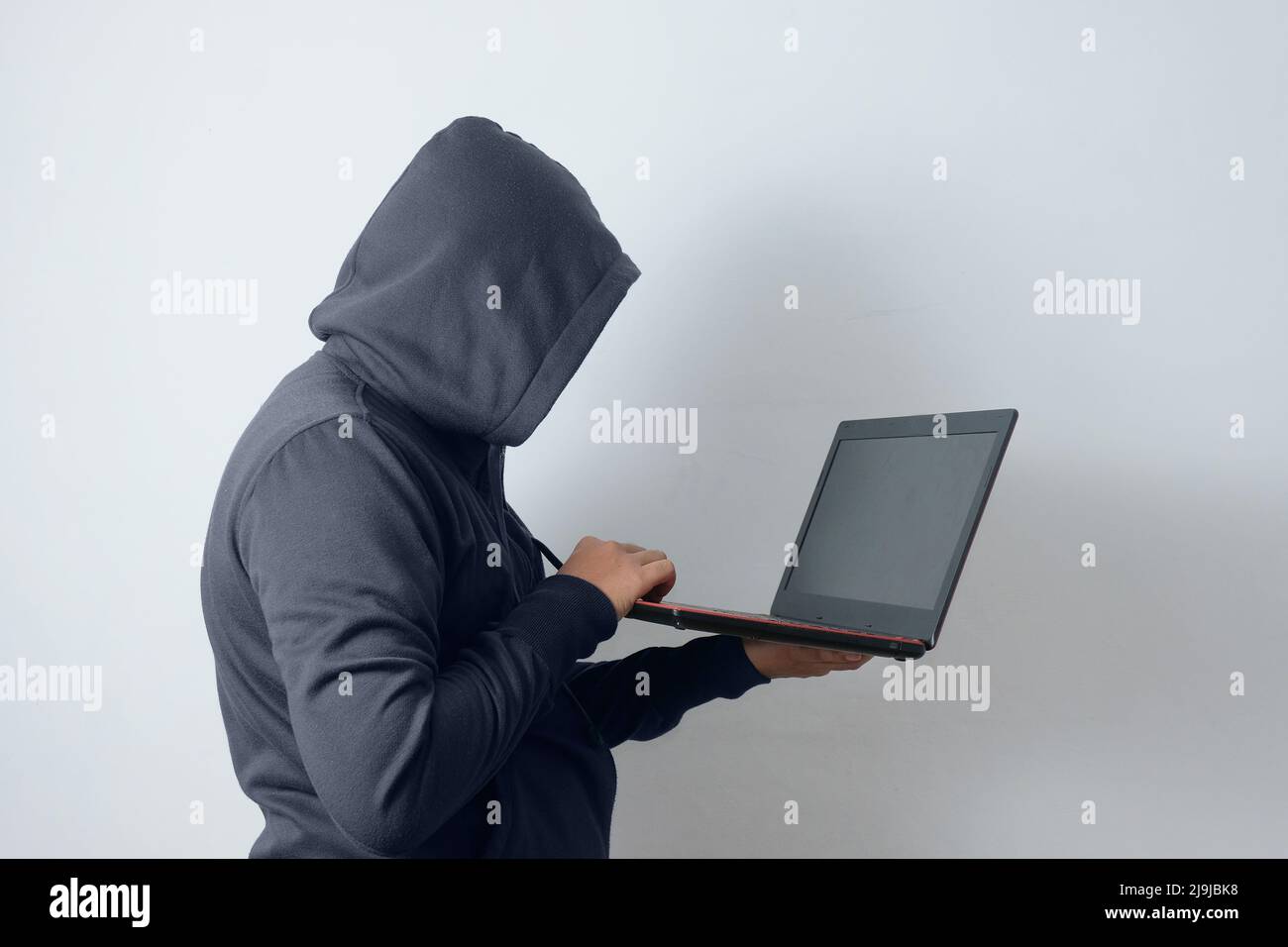 Geheimnisvoller Mann mit Hoodie und Laptop Stockfoto
