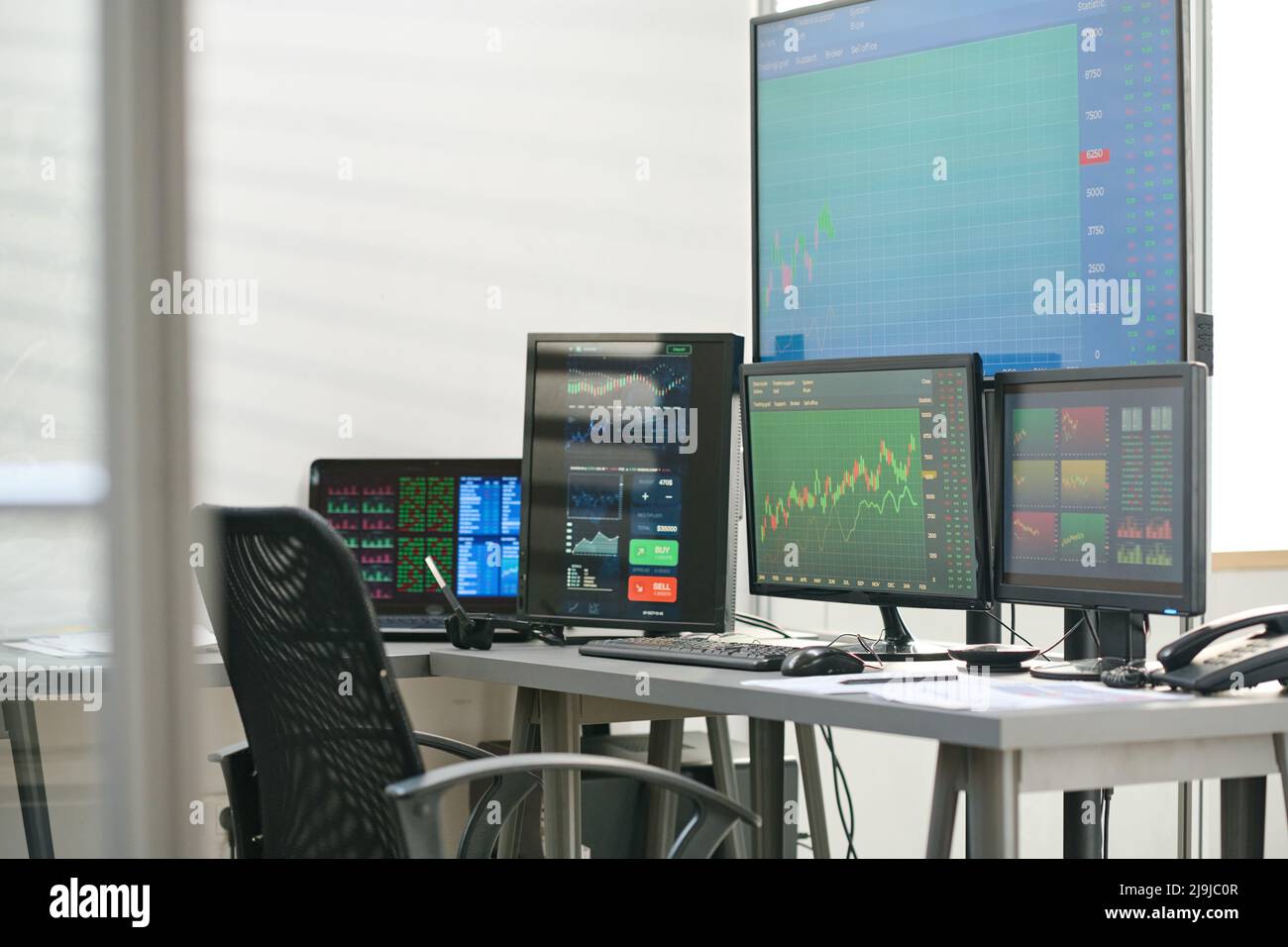 Keine Menschen, die von Spezialisten für den modernen Aktien- und Devisenhandel aufgenommen wurden, arbeiten im modernen Büro mit Schreibtisch, Computer und Computermonitoren Stockfoto