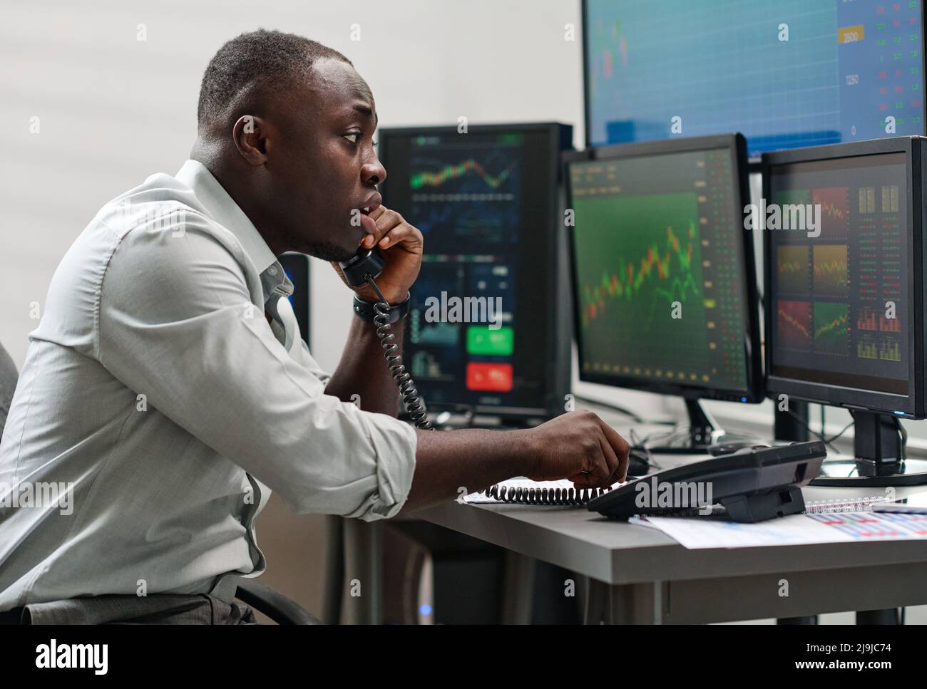 Junger afroamerikanischer Mann, der in einem Maklerunternehmen arbeitet, hat Probleme, telefonisch über Probleme zu sprechen Stockfoto