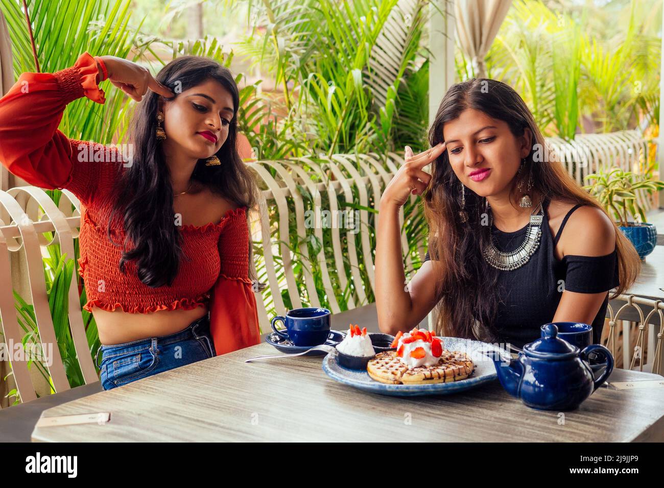 Traurige modische indische Freunde Paar von zwei Frauen, die cakes.friends lang erwartete Treffen Klatsch Studenten essen Pfannkuchen trinken Masala Tee zu sehen Stockfoto