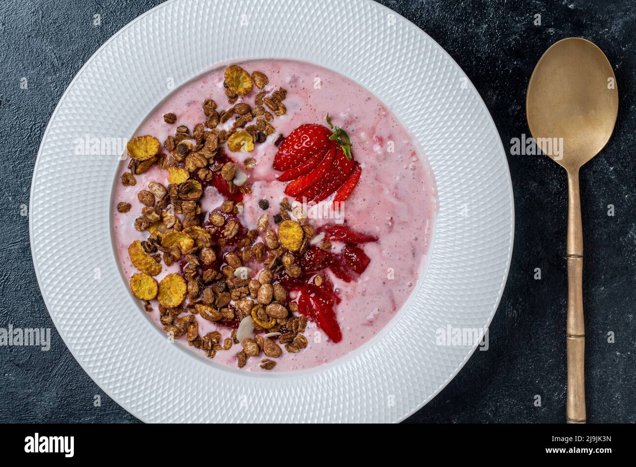 Weißer Teller mit roten Erdbeeren, Müsli und natürlichem Joghurt auf schwarzem Hintergrund, Nahaufnahme, Draufsicht Stockfoto