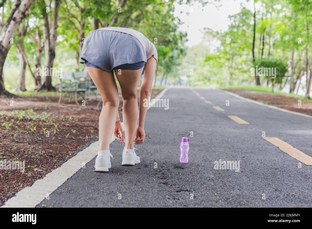 Frau schnürt ihre Schnürsenkel vor dem Training im Park. Stockfoto