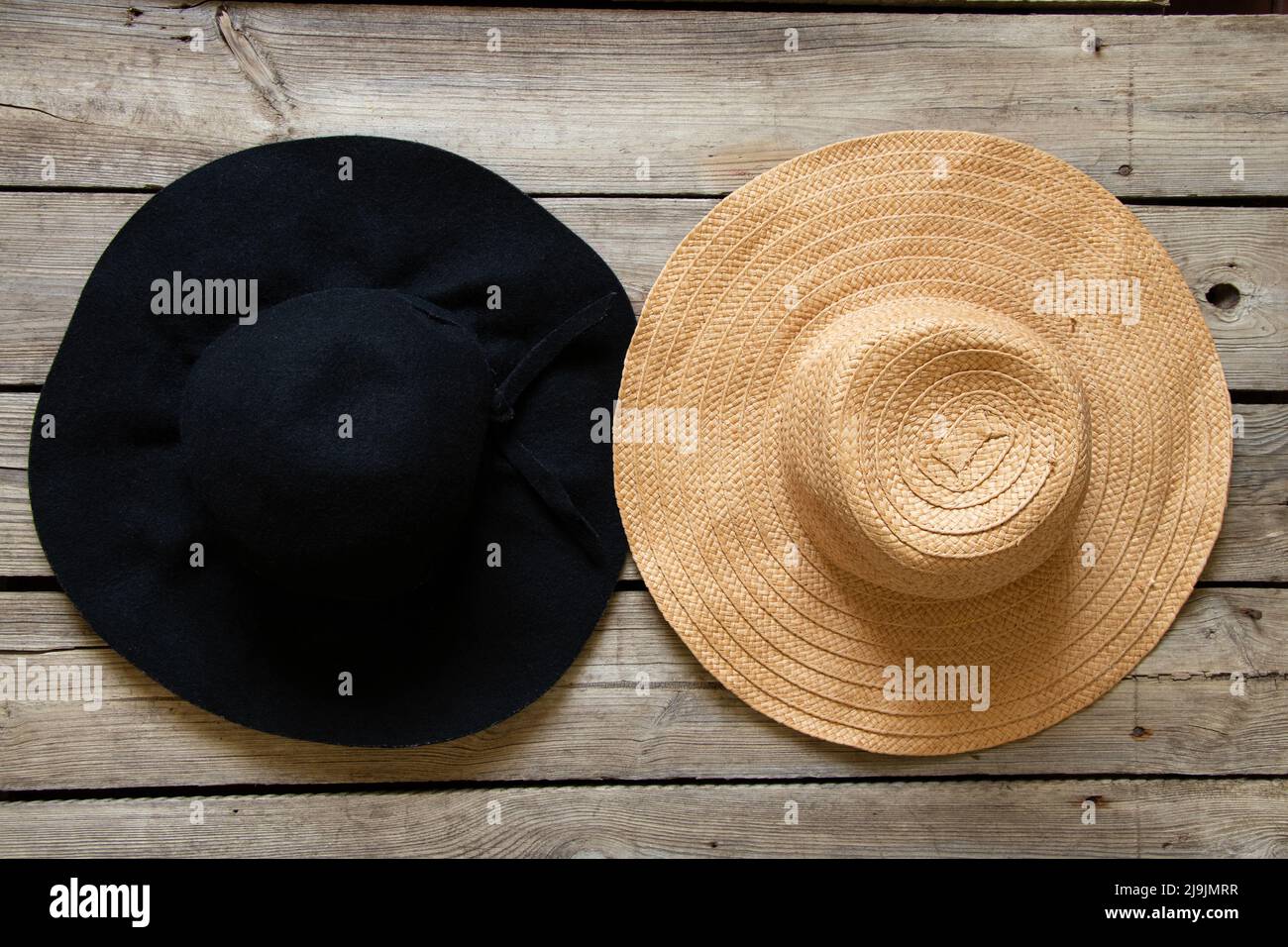 Schwarzer Hut und Strohhut auf Holztisch, zwei verschiedene Hüte, Mode und Schönheit Stockfoto