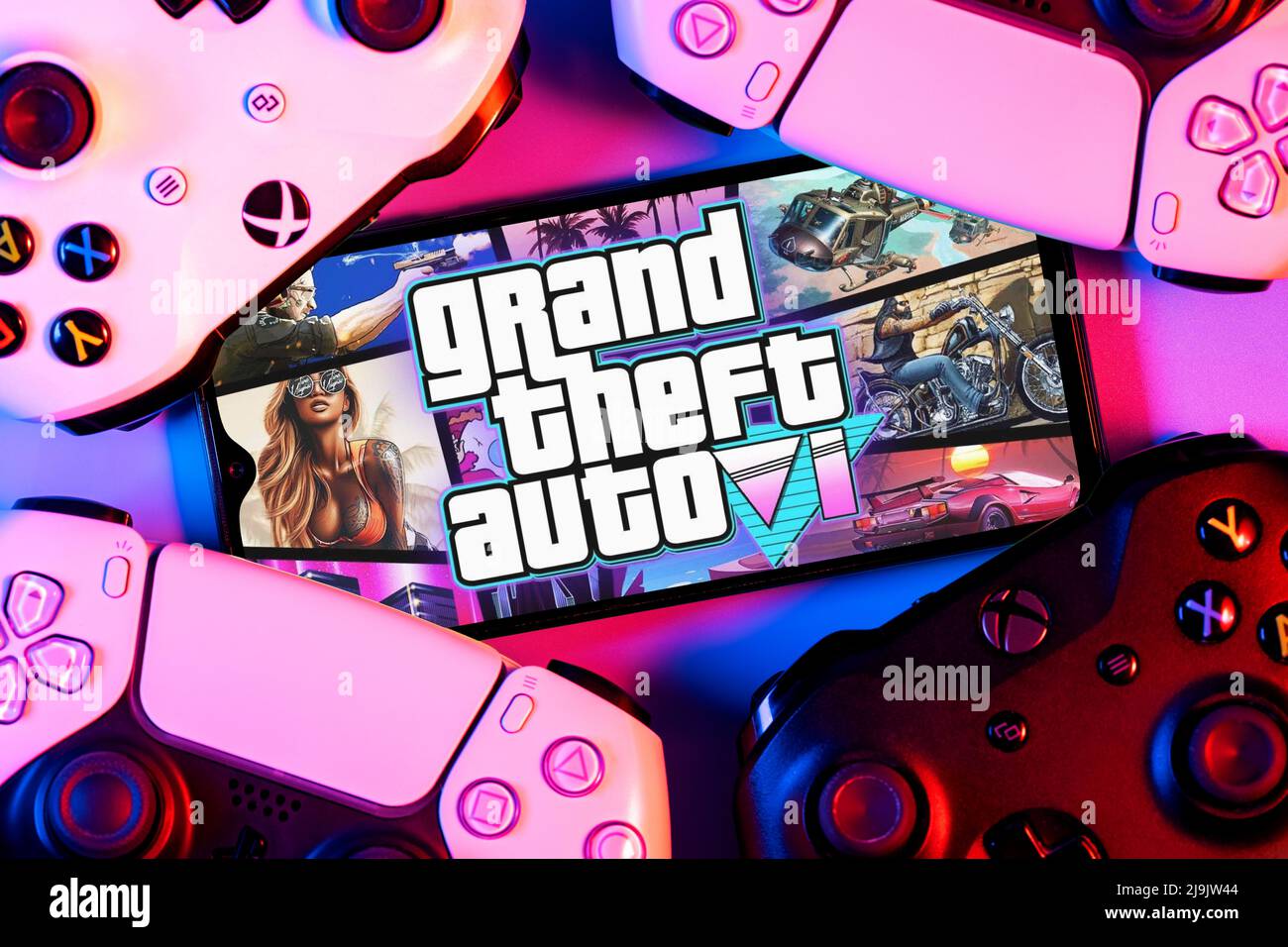 Smartphone mit GTA 6-Logo auf dem Bildschirm, umgeben von Gamepads Stockfoto