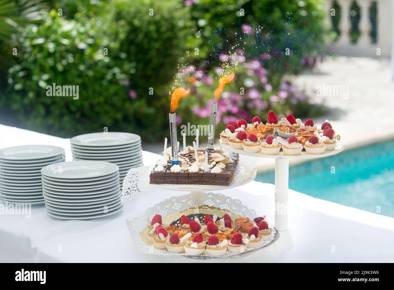 Dessertbuffet, kleine Schokolade- und Erdbeerkuchen, Geburtstagskerzen am Pool. Stockfoto
