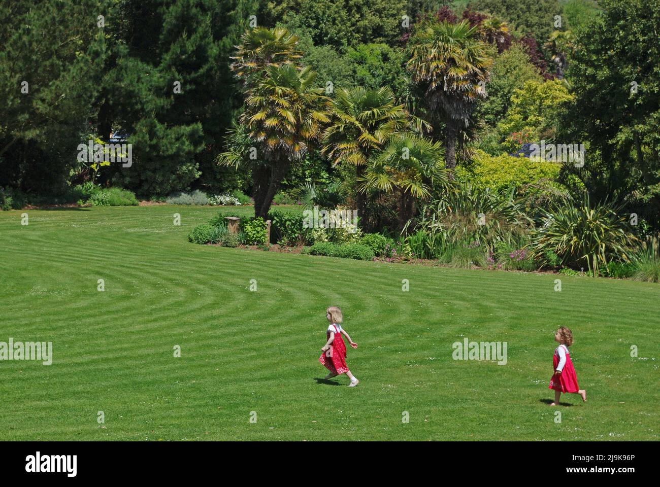 Abbotsbury Subtropical Gardens, Abbotsbury, Dorset, Großbritannien; zwei junge Mädchen laufen über den Rasen. Stockfoto