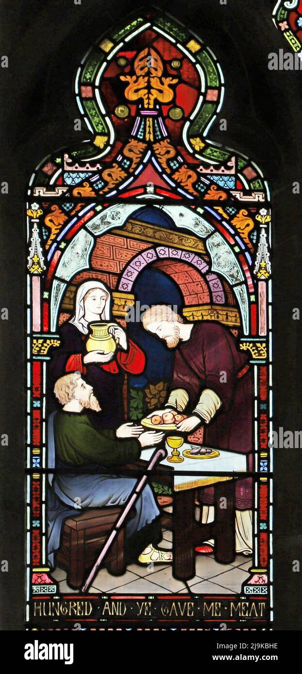Ein Buntglasfenster von Frederick Preedy, das Corporal Acts of Mercy, St Peter and St Paul's Church, King's Sutton, Northamptonshire, zeigt Stockfoto