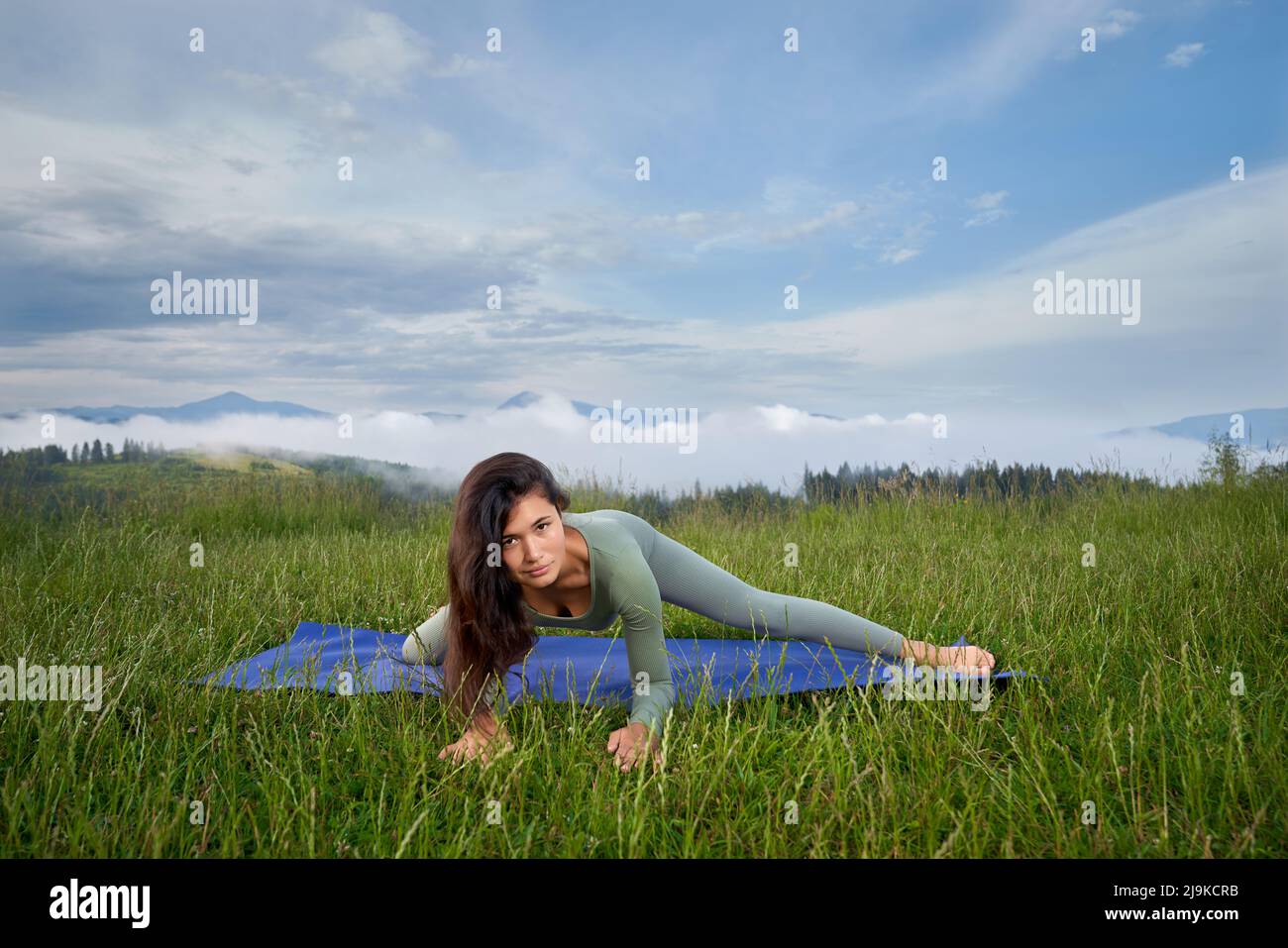 Gesunde und fit Frau in Sportkleidung, die im Sommer flexible Übungen auf Yogamatte macht. Konzept der Menschen, Training und eine gesunde Lebensweise. Stockfoto