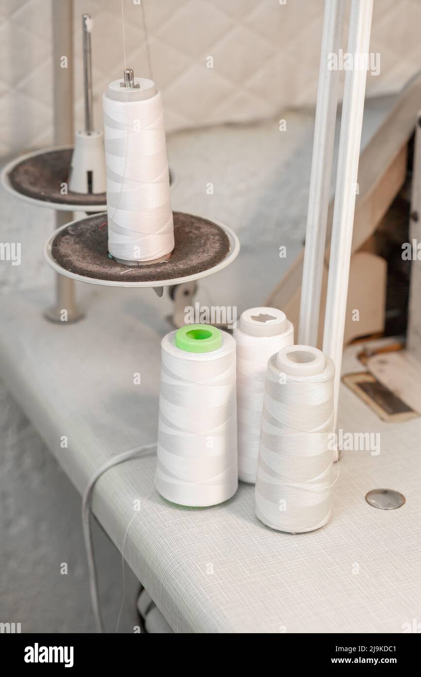 Rollen mit weißen Fäden für eine Nähmaschine auf einem Stand im Werker. Stockfoto