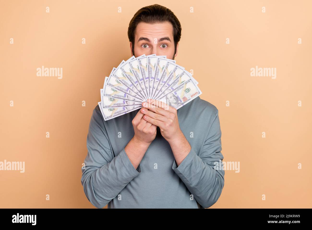 Foto von jungen Mann wohlhabenden Cover Gesicht Geld Gewinn Nutzen Gehalt isoliert über beige Farbe Hintergrund Stockfoto