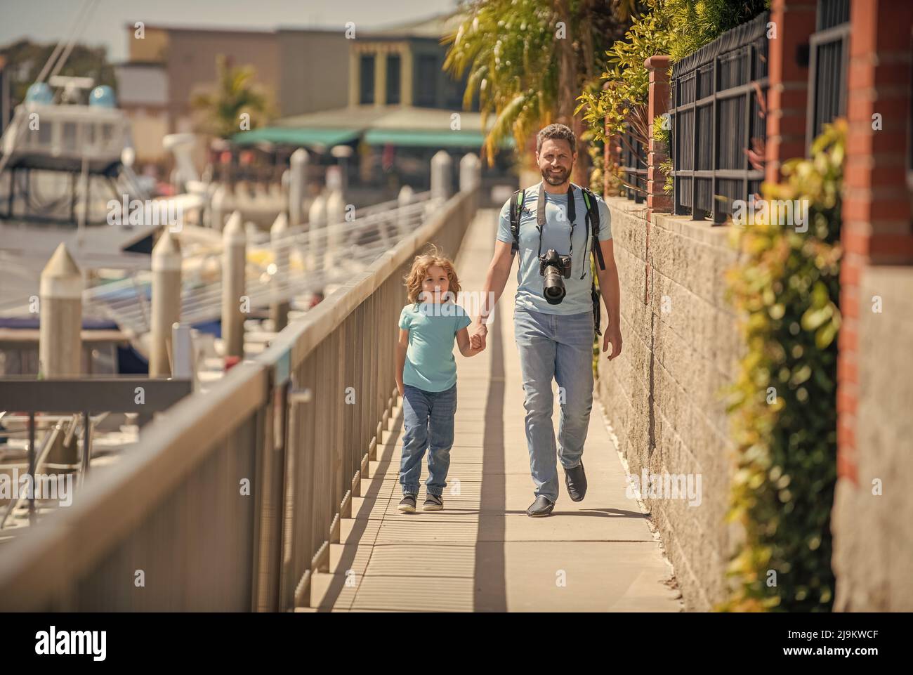 Urlaubsreisende. Mann und Junge halten sich die Hände auf der Promenade. Freizeitaktivitäten. Vater und Sohn Kind Stockfoto