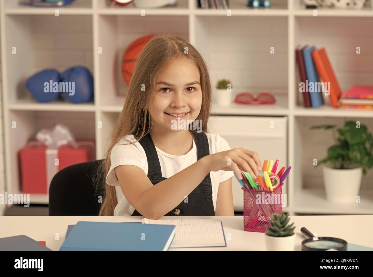 Glückliches Kind, das Briefpapier in der Schule im Klassenzimmer nimmt, Uniform tragen, studieren Stockfoto