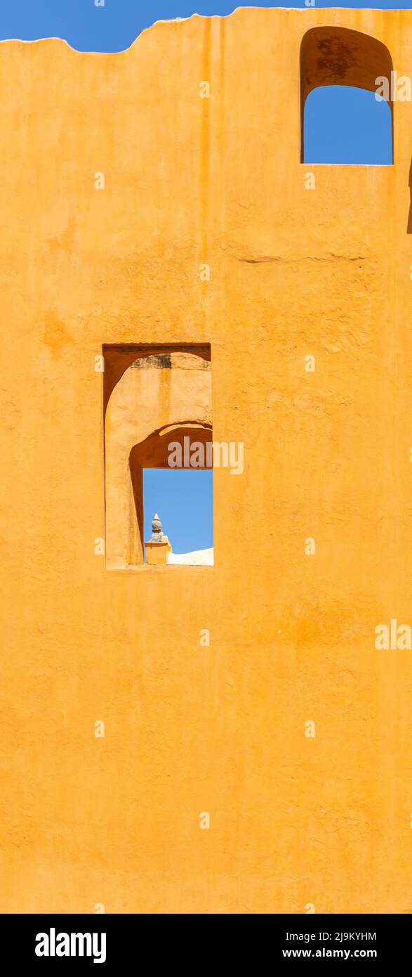 Vertikales Foto einer gelben Wand mit Fenstern und blauem Himmel Stockfoto