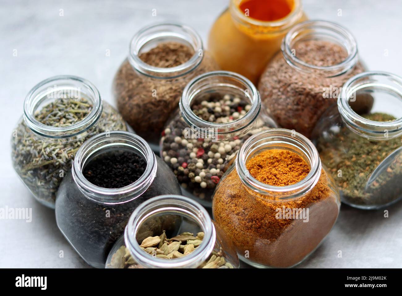 Kleine Gläser mit verschiedenen Gewürzen. Peppercorn, Kardamom, Kurkuma, Curry, Leinsamen, Kurkuma Nahaufnahme Foto. Stockfoto