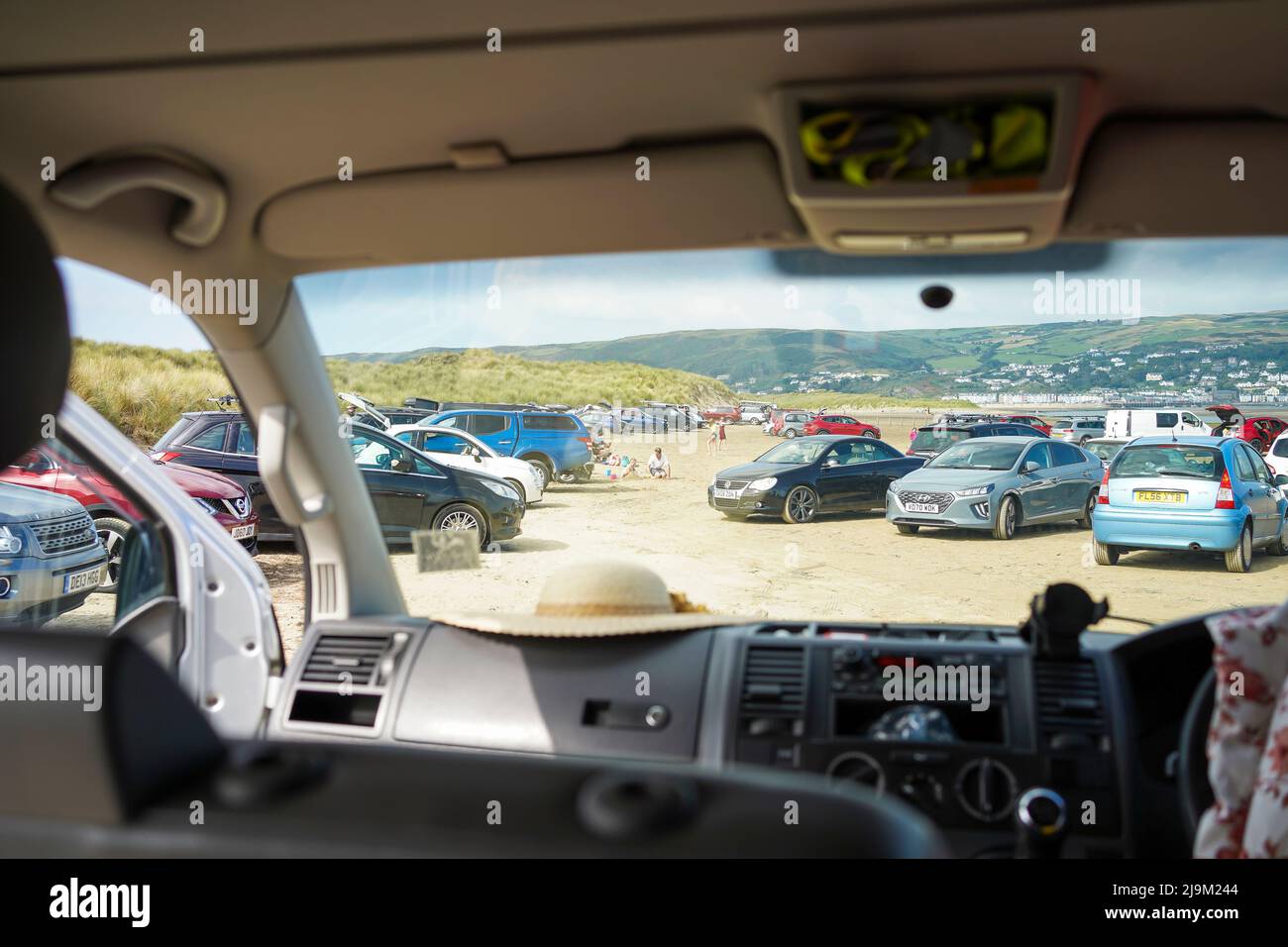 Blick aus dem Inneren eines VW Transporter Wohnwagens, Blick auf Autos, die im Ynysidas Nature Reserve, Wales, Großbritannien, auf dem Sand geparkt sind. Stockfoto