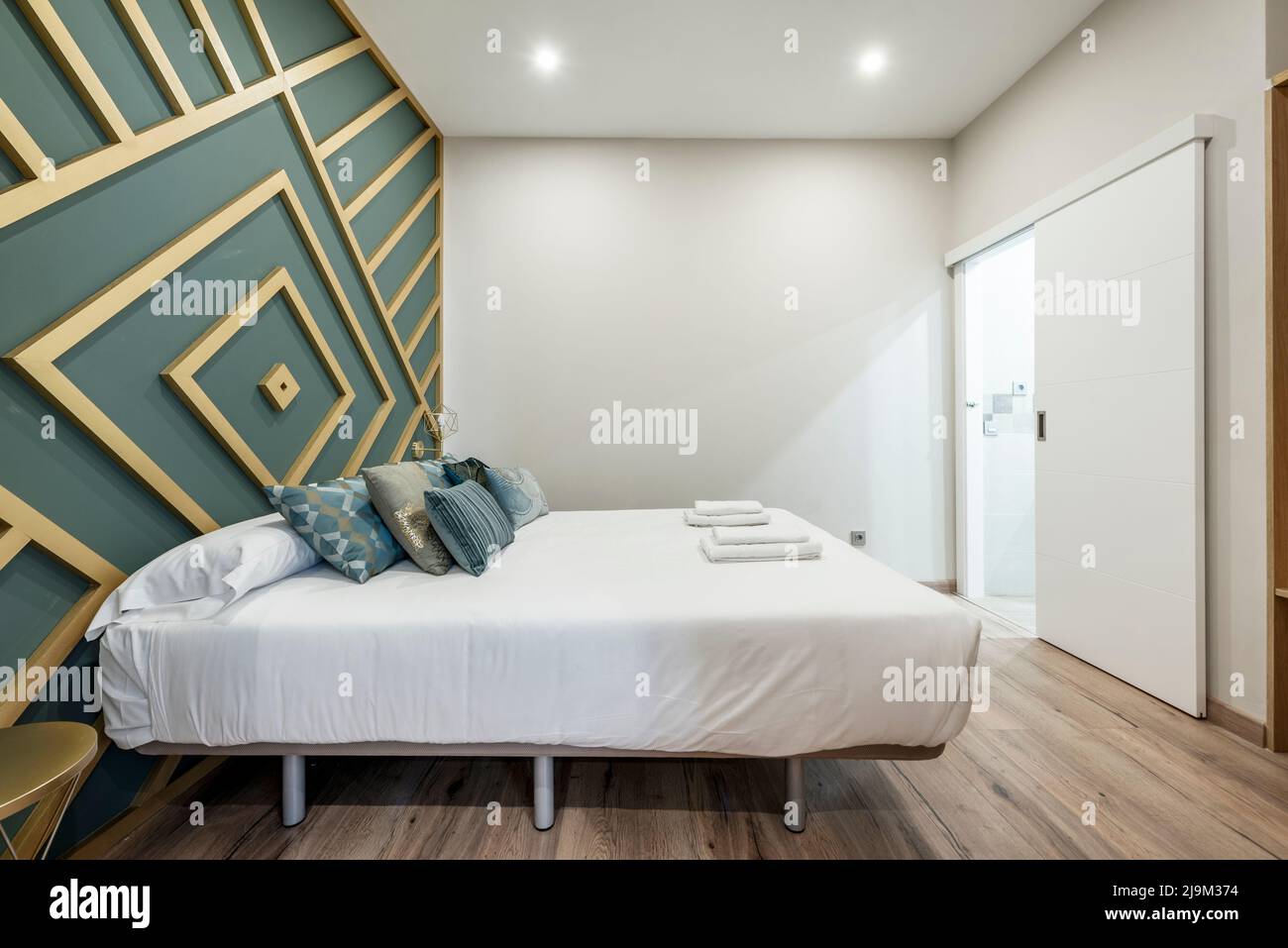 Schlafzimmer mit Doppelbett mit Polsterung, Kopfteil mit goldlackiertem  Holz und grüner Wand Stockfotografie - Alamy