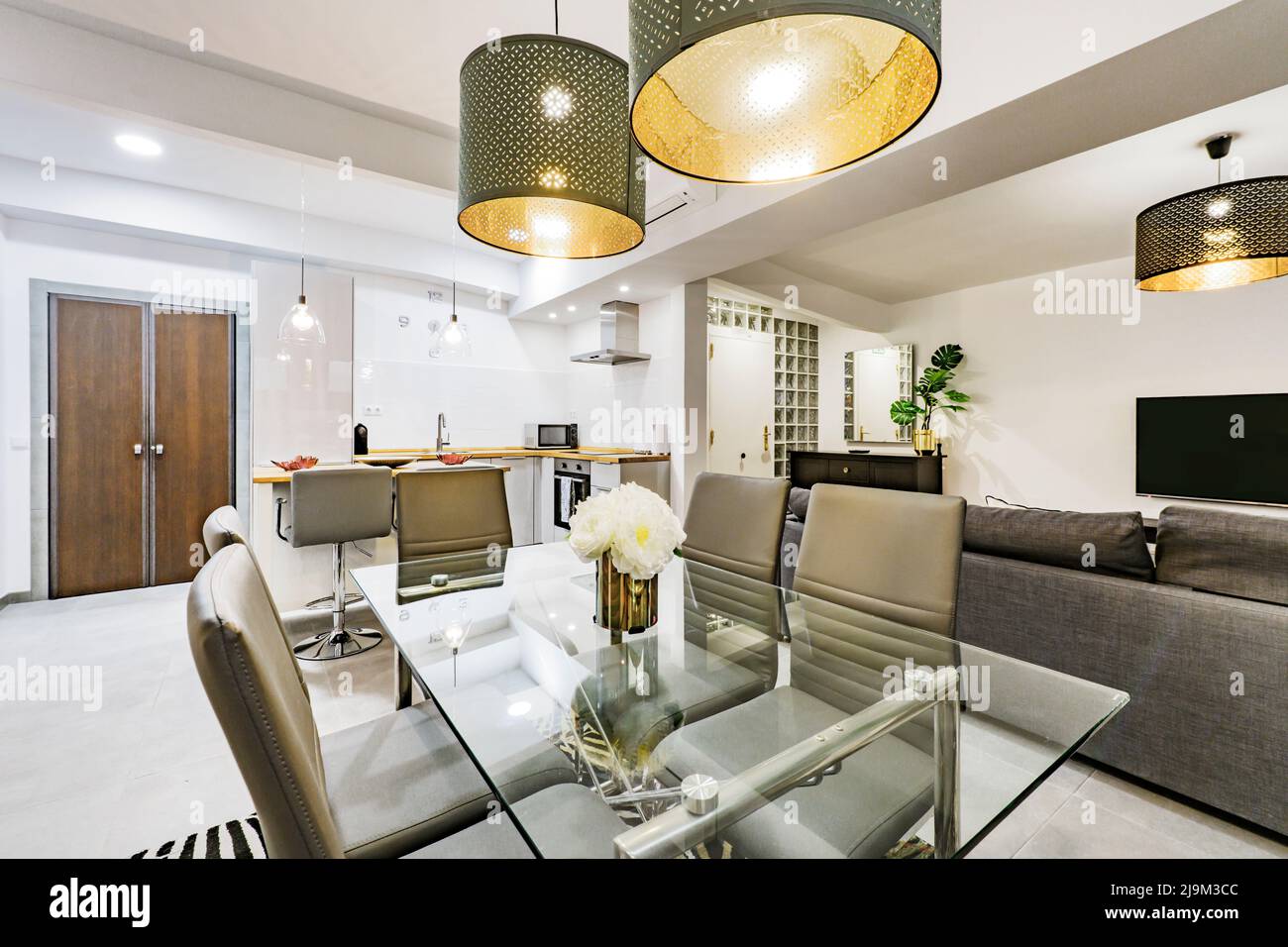 Design-Apartment-Wohnzimmer mit Esstisch aus Glas, grauen Ledersesseln und dekorativen Lampen Stockfoto