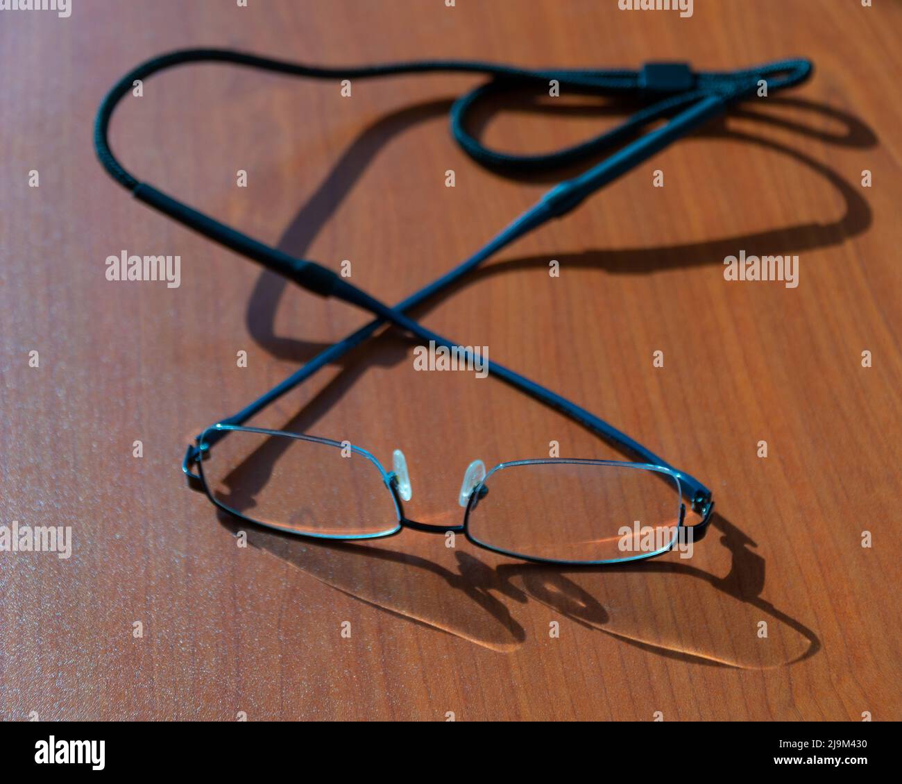 Augenbrille mit Nackenband auf einem braunen Holztisch mit selektivem Fokus. Stockfoto