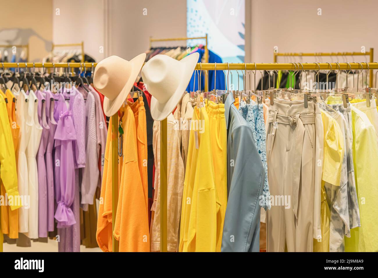 Bunte Jugendkleidung auf Kleiderbügeln im Geschäft, Sommer- und Frühlingssortiment im Bekleidungsgeschäft Stockfoto