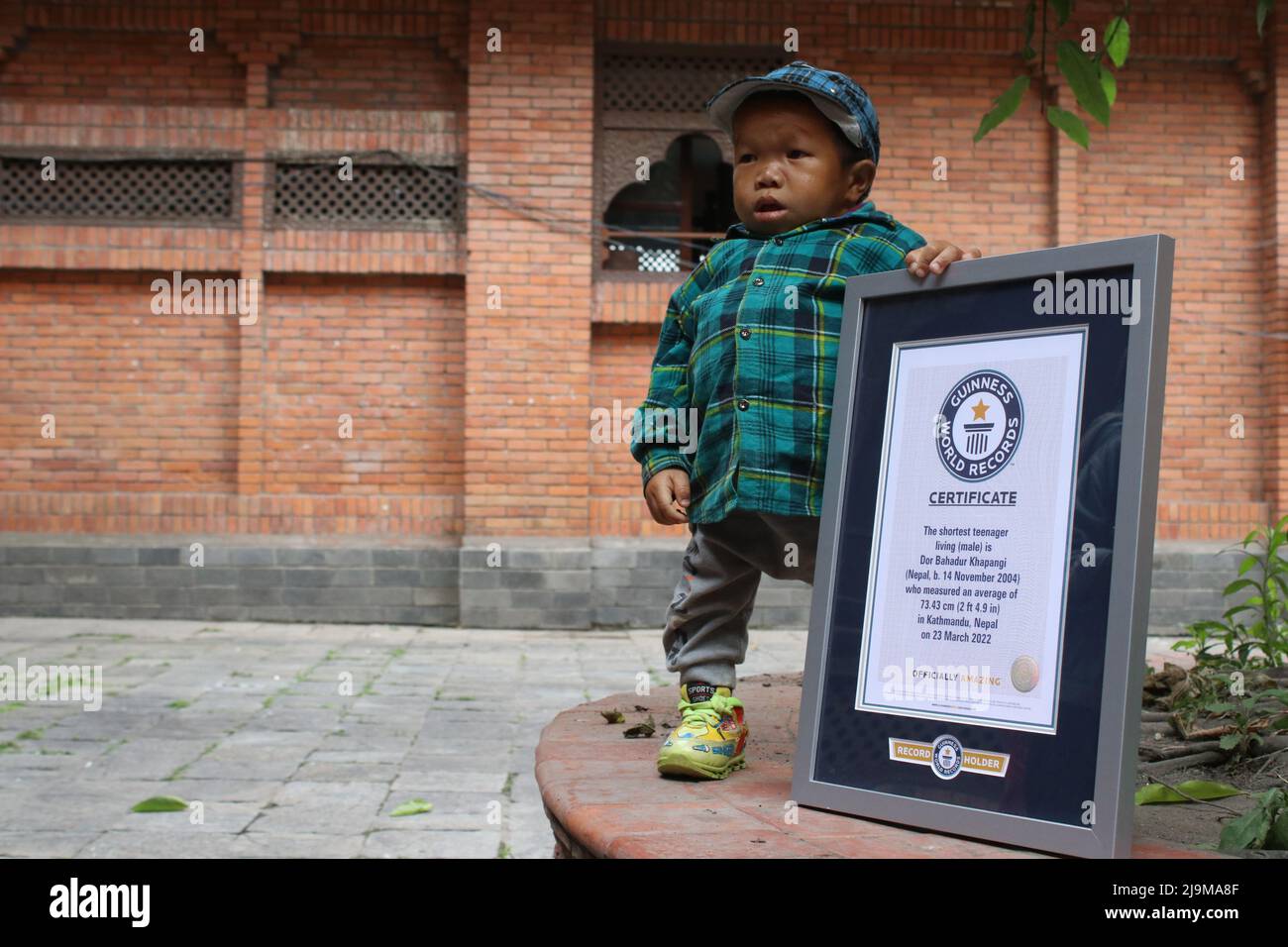 Kathmandu, Nepal. 24.. Mai 2022. Am 24. Mai 2022 in Kathmandu, Nepal. Der Guinness-Weltrekordhalter der kürzesten lebenden Männer des Teenagers Dor Bahadur Khapangi hält das Guinness-Weltrekordzertifikat, während er bei der Vorbereitung des nepalesischen Tourismusbüros für das Foto posiert. Er misst die Khapangi-Höhe und beträgt 73,43 cm (2ft 4,9 Zoll) (Foto: Abhishek Maharjan/Sipa USA) Quelle: SIPA USA/Alamy Live News Stockfoto
