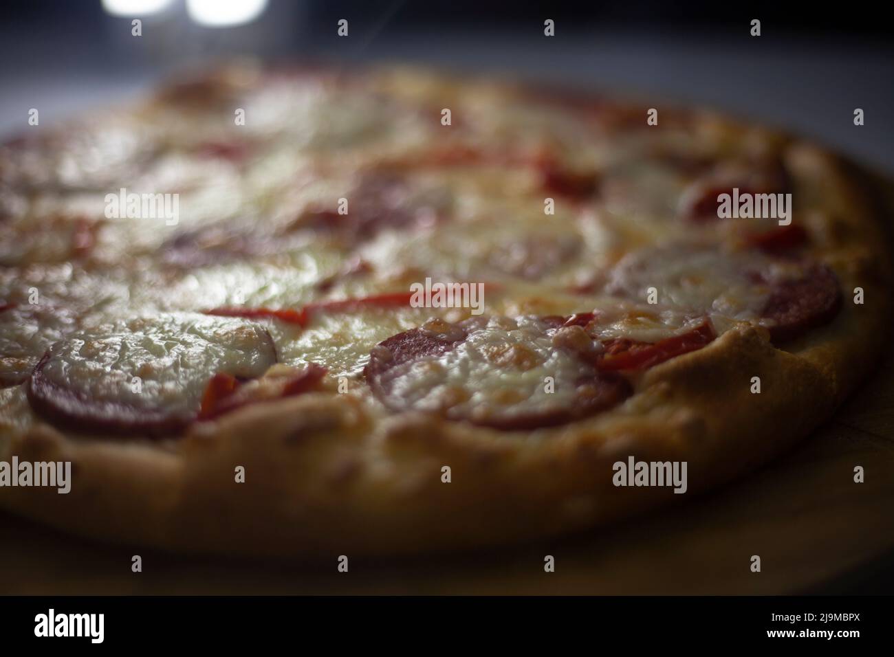 Pizza an der Theke. Essen mit Käse und Wurst. Gebratene Pizza in der Küche. Gebackene Lebensmittel mit hohem Fettgehalt. Stockfoto