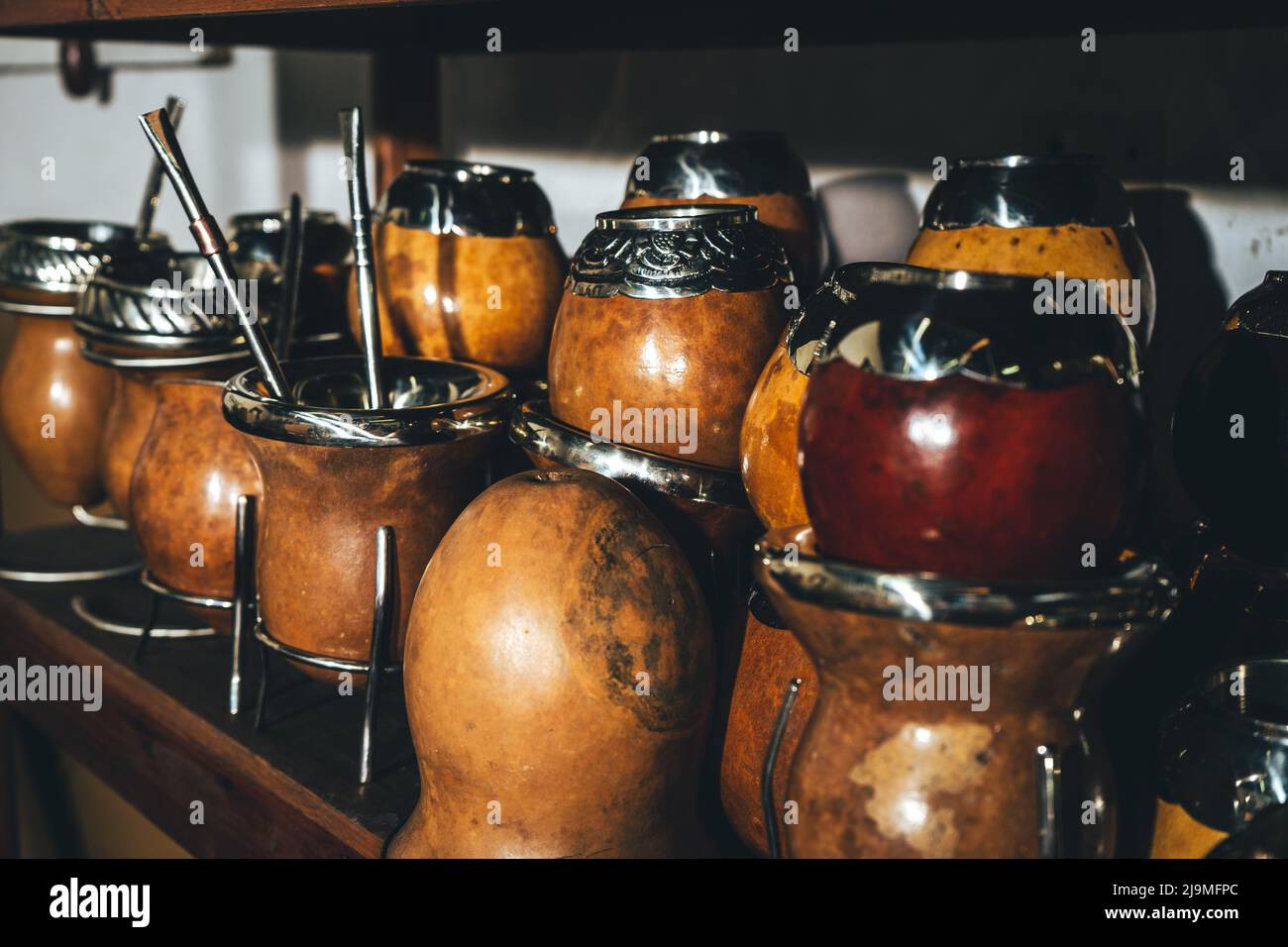 Kollektion von Mate Kürbis Cups mit handgefertigten silbernen Felgen und Trinkhalmen auf Regal in der Werkstatt platziert Stockfoto