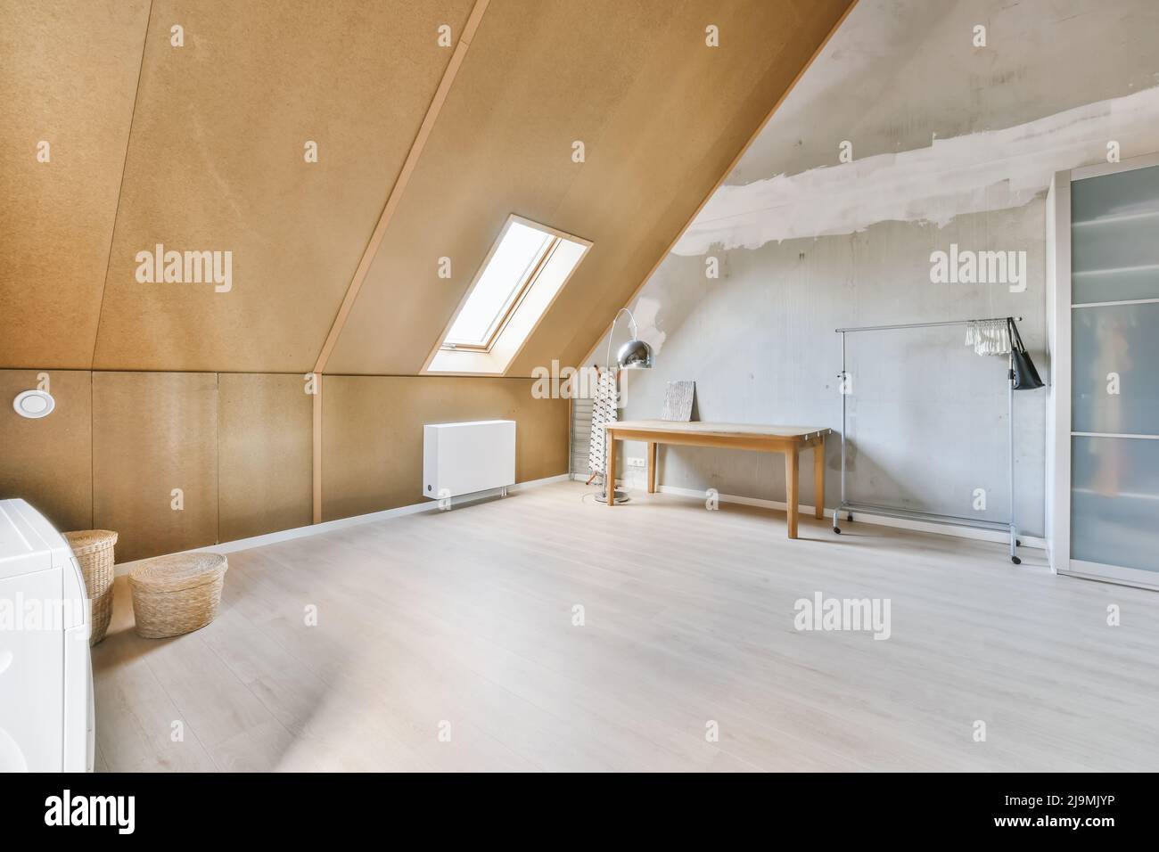 Kleiderschrank mit durchsichtigen Türen in der Nähe von leerer Schiene und  Tisch in geräumigen hellen Dachgeschoss Zimmer des Hauses Stockfotografie -  Alamy