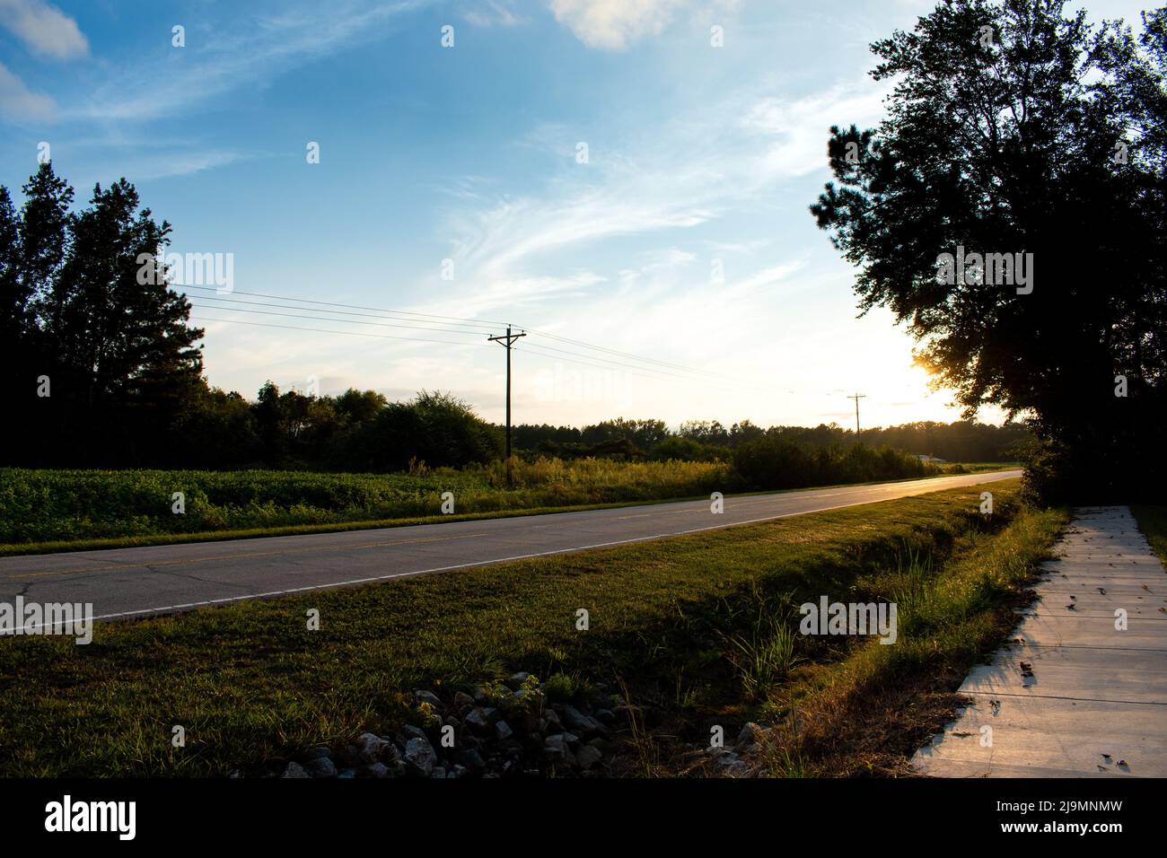 Blick auf die Straße vom Bürgersteig an einem schönen Tag mit klarem blauen Himmel und Wolken Stockfoto