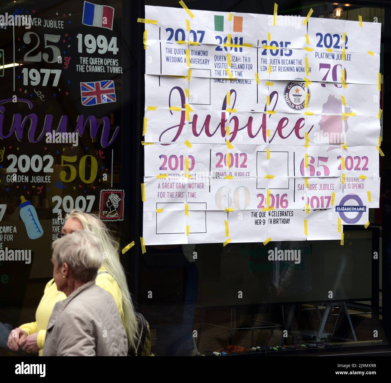 Manchester, Großbritannien, 24.. Mai 2022. Eine Zeitleiste mit der Regierungszeit der Königin im Fenster einer Lloyd's Bank und eines Cafés im Zentrum von Manchester, Großbritannien. Text und Bilder auf den Papierblättern auf der rechten Seite ermöglichen es jemandem, diese auf dem Fenster zu malen, wie links zu sehen. Im Jahr 2022 wird Ihre Majestät die Königin der erste britische Monarch, der nach 70 Jahren seines Dienstes ein Platin-Jubiläum feiert. Quelle: Terry Waller/Alam Stockfoto Manchester, Großbritannien, 24.. Mai 2022. Eine Zeitleiste mit der Regierungszeit der Königin im Fenster einer Lloyd's Bank und eines Cafés im Zentrum von Manchester, Großbritannien. Text und Bilder auf den Papierblättern auf der rechten Seite ermöglichen es jemandem, diese auf dem Fenster zu malen, wie links zu sehen. Im Jahr 2022 wird Ihre Majestät die Königin der erste britische Monarch, der nach 70 Jahren seines Dienstes ein Platin-Jubiläum feiert. Quelle: Terry Waller/Alam Stockfoto