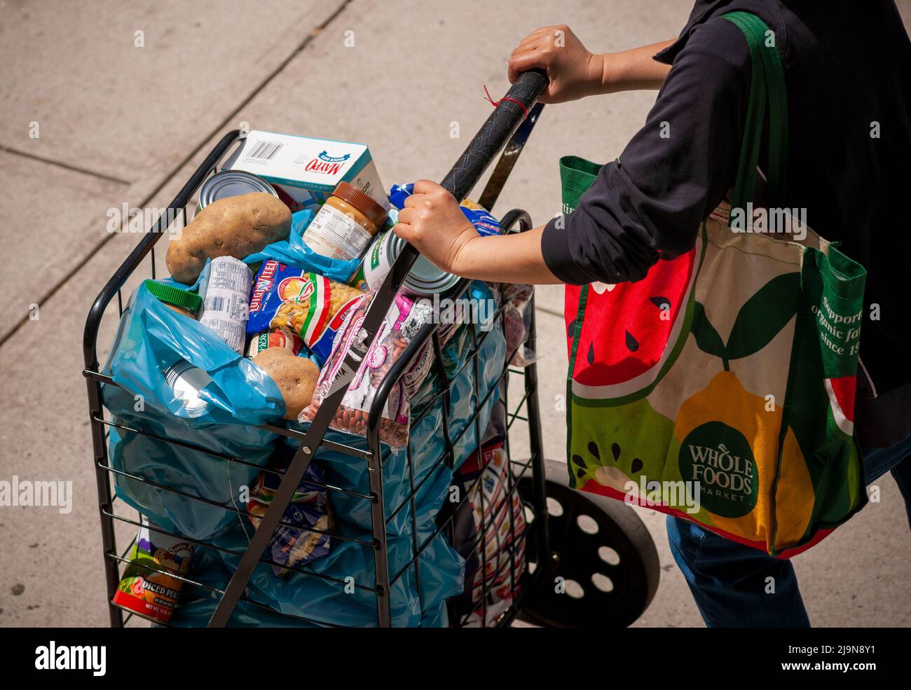 Eine Kundin mit einem Warenkorb, der mit ihrer Großzügigkeit von der Holy Apostles Food Pantry in Chelsea in New York am Dienstag, den 17. Mai 2022 gefüllt war. .(© Richard B. Levine) Stockfoto