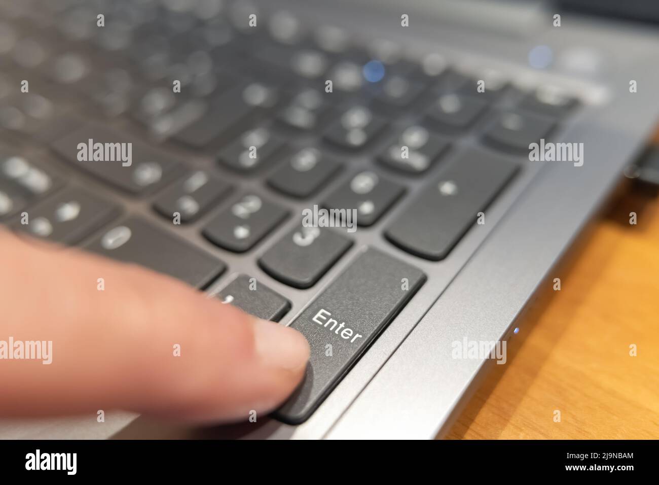 Drücken Sie mit dem Finger die ENTER-Taste auf einem Computer, einem Makrofoto. Stockfoto