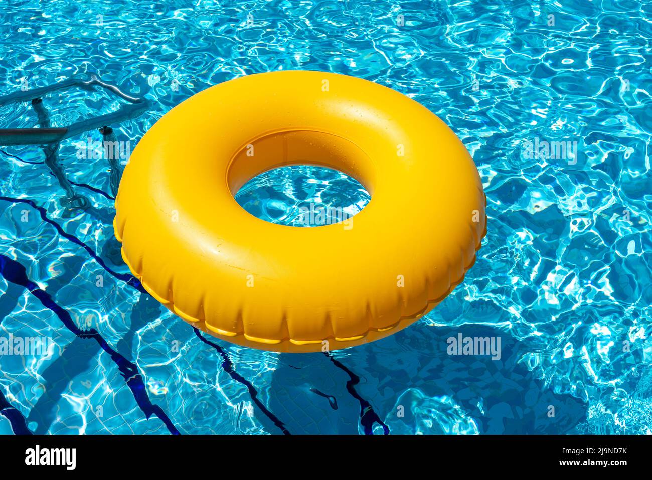 Gelber Ring schwimmt im erfrischenden blauen Swimmingpool Stockfoto