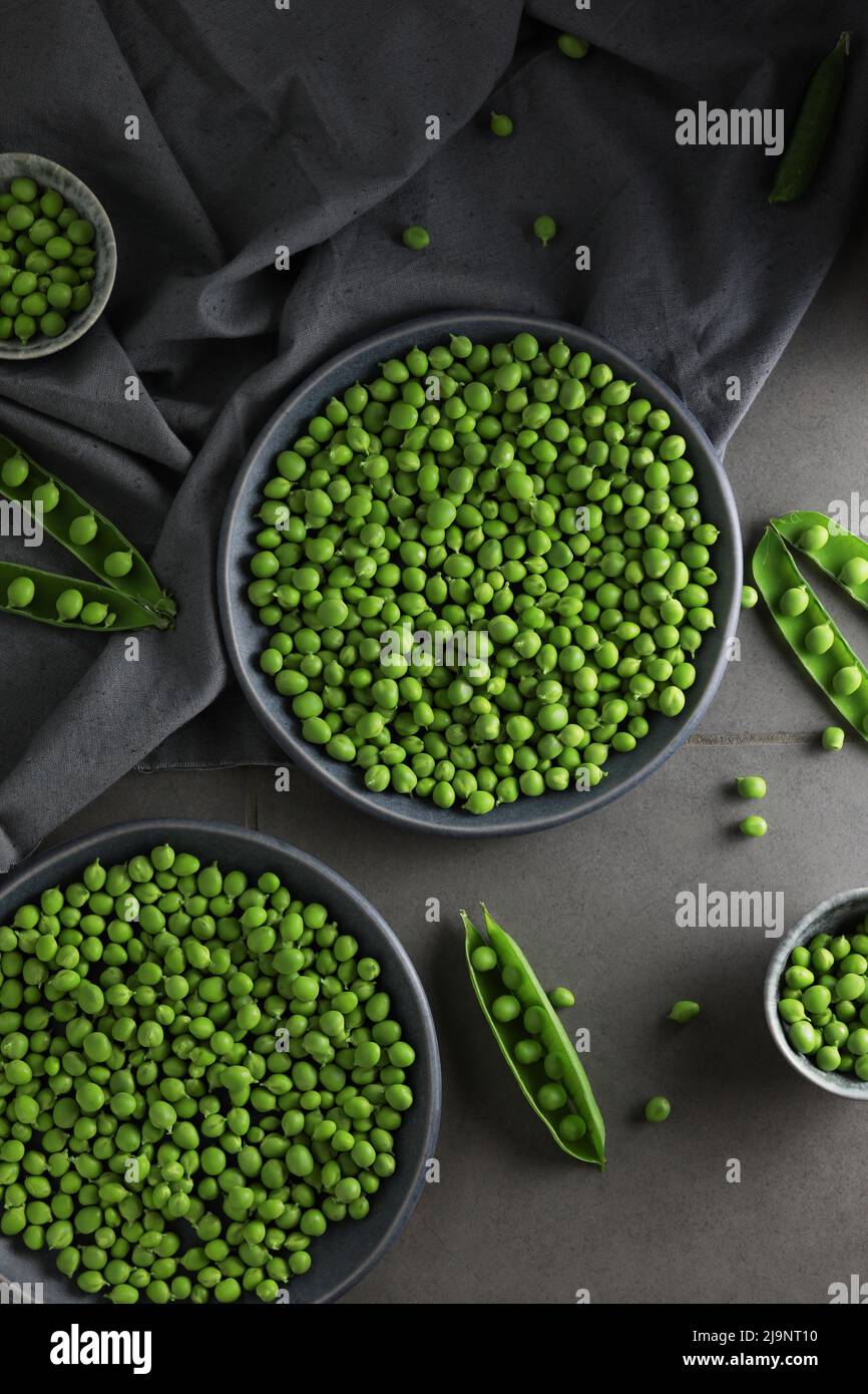 Frische grüne Erbsen in Tellern auf grauem Grund. Draufsicht. Stockfoto