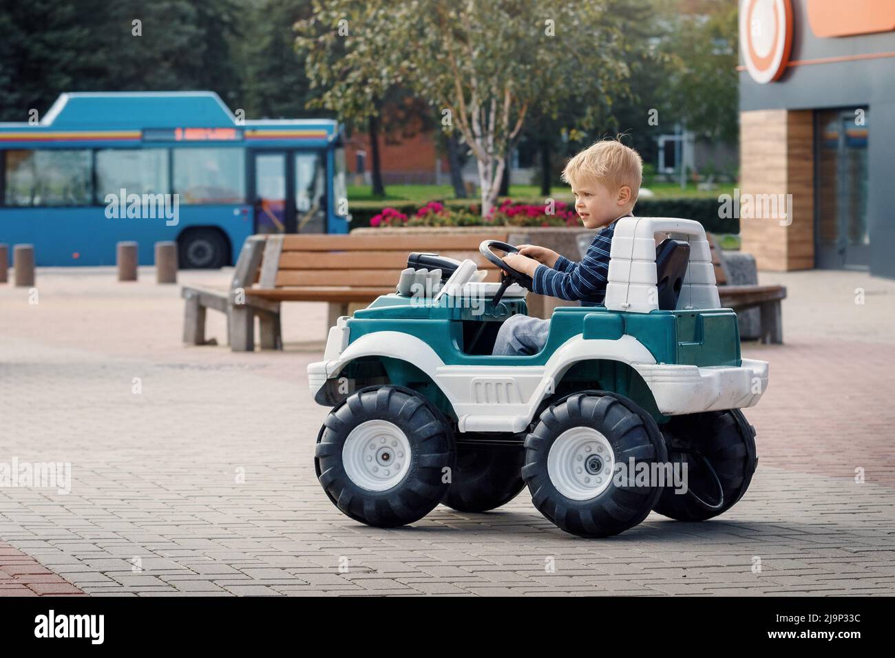 Lustiger Junge fährt auf einem Spielzeug-Elektroauto. Junges Kind Porträt mit Spielzeug Auto. Das Konzept einer glücklichen Kindheit. Stockfoto