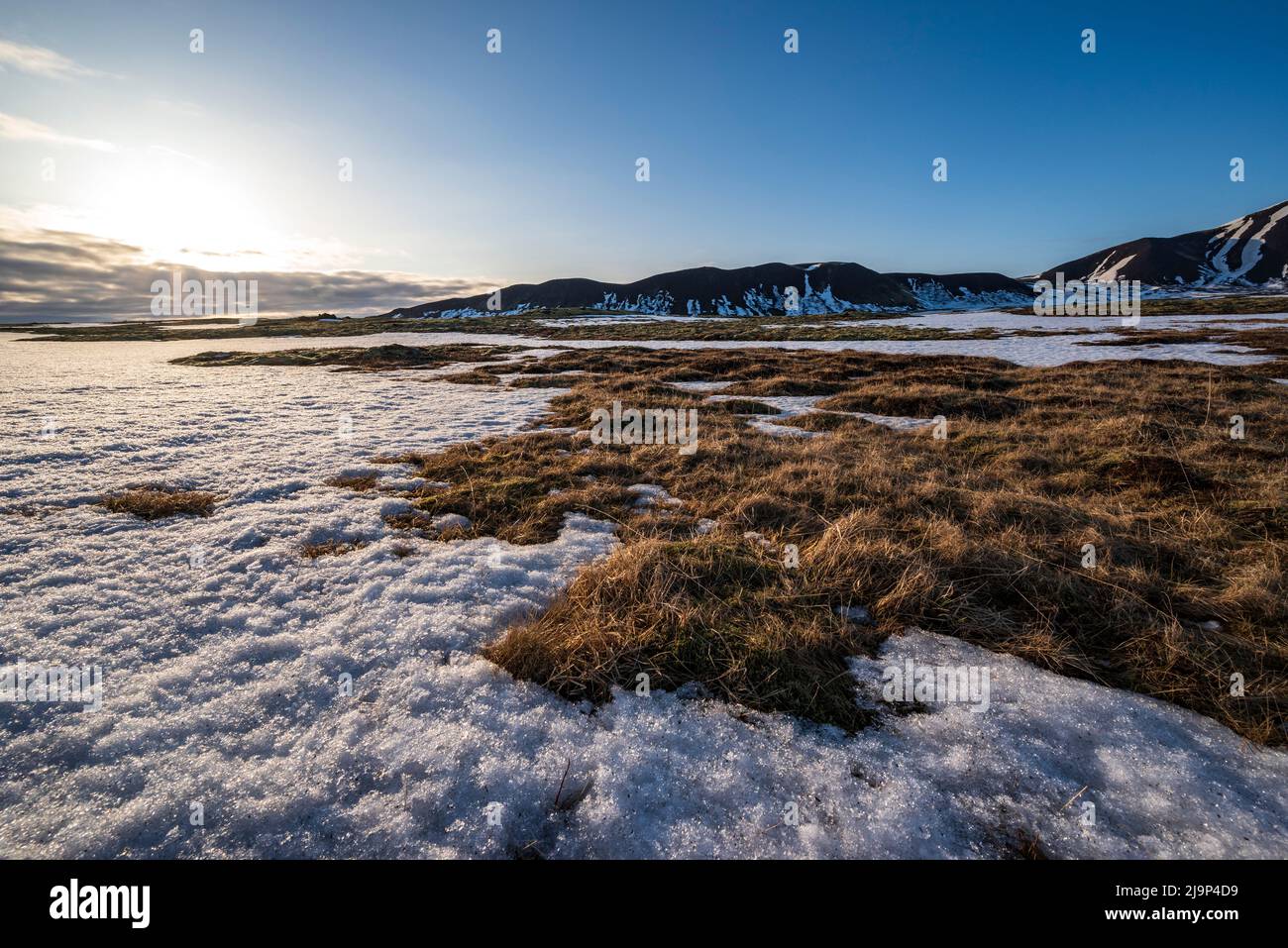 Schönes Abendlicht über einem Schneefeld bei Sonnenaufgang mit Bergen im Hintergrund, neben der Route 365 zwischen Laugarvatn und Thingvellir, Island Stockfoto