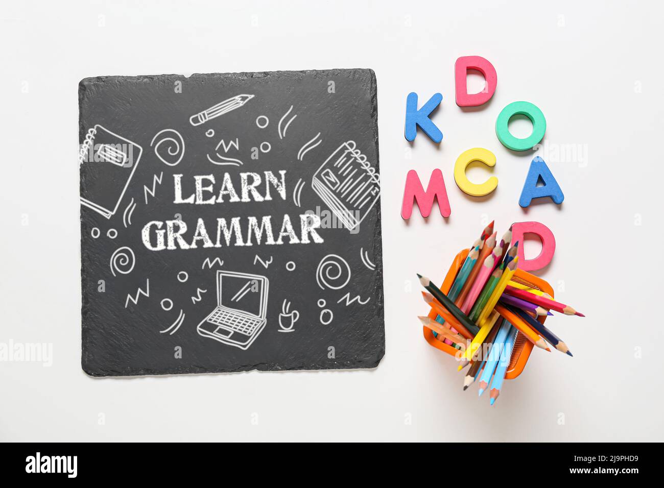 Schwarzes Brett mit Text GRAMMATIK LERNEN und verschiedene Schreibwaren auf weißem Hintergrund Stockfoto