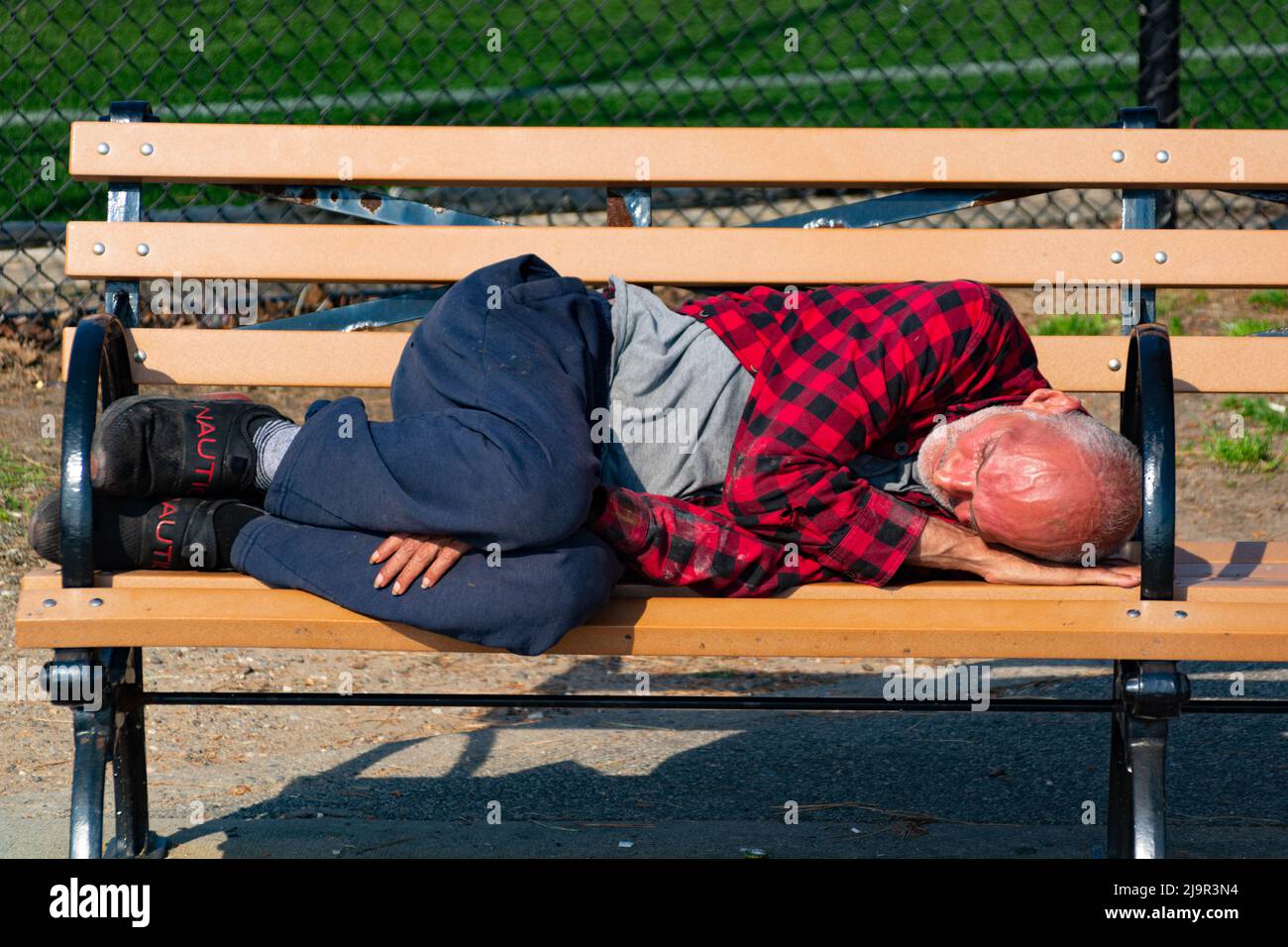 Ein betrunkener Mann schläft auf der Bank in Brooklyn Stockfoto
