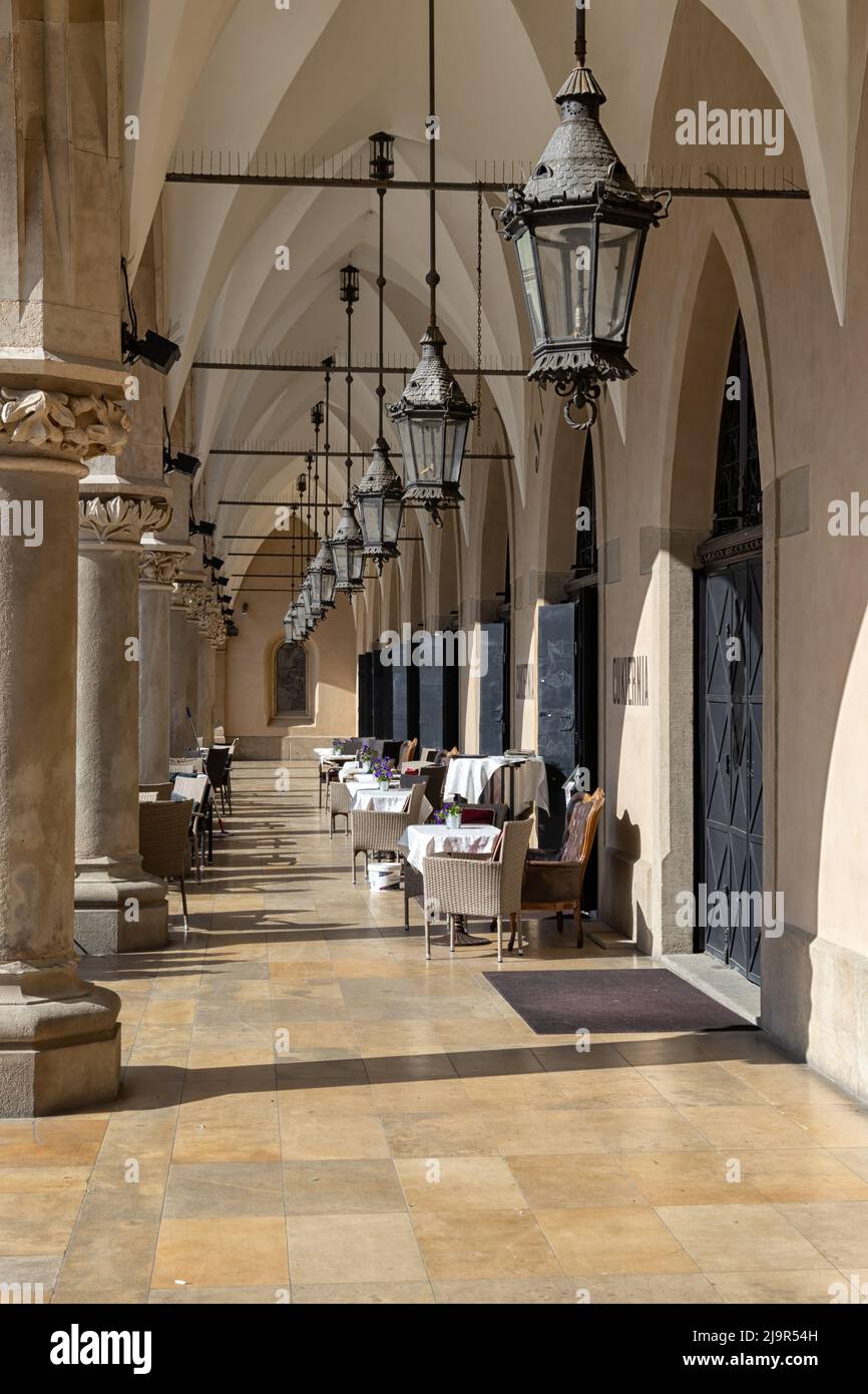 KRAKAU, POLEN - 16. MAI 2022: Cafétische gewölbte Arkade der Tuchhalle auf dem Hauptplatz Stockfoto
