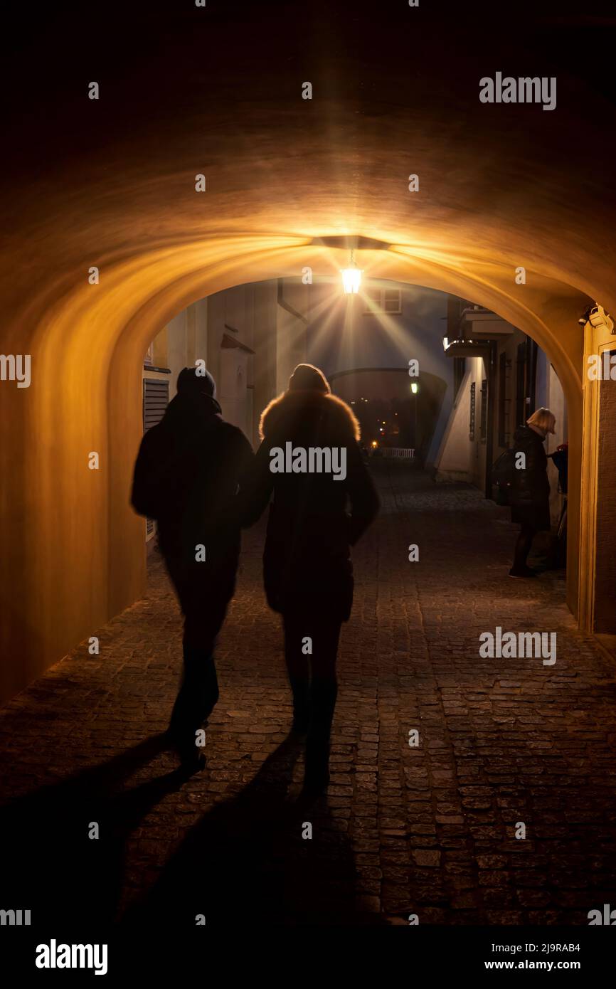 Paar am späten Abend Spaziergang durch eine Lampe beleuchteten Durchgang unter Mietshaus auf Kopfsteinpflaster Dawna Straße in der Altstadt von Warschau Stadt in P Stockfoto
