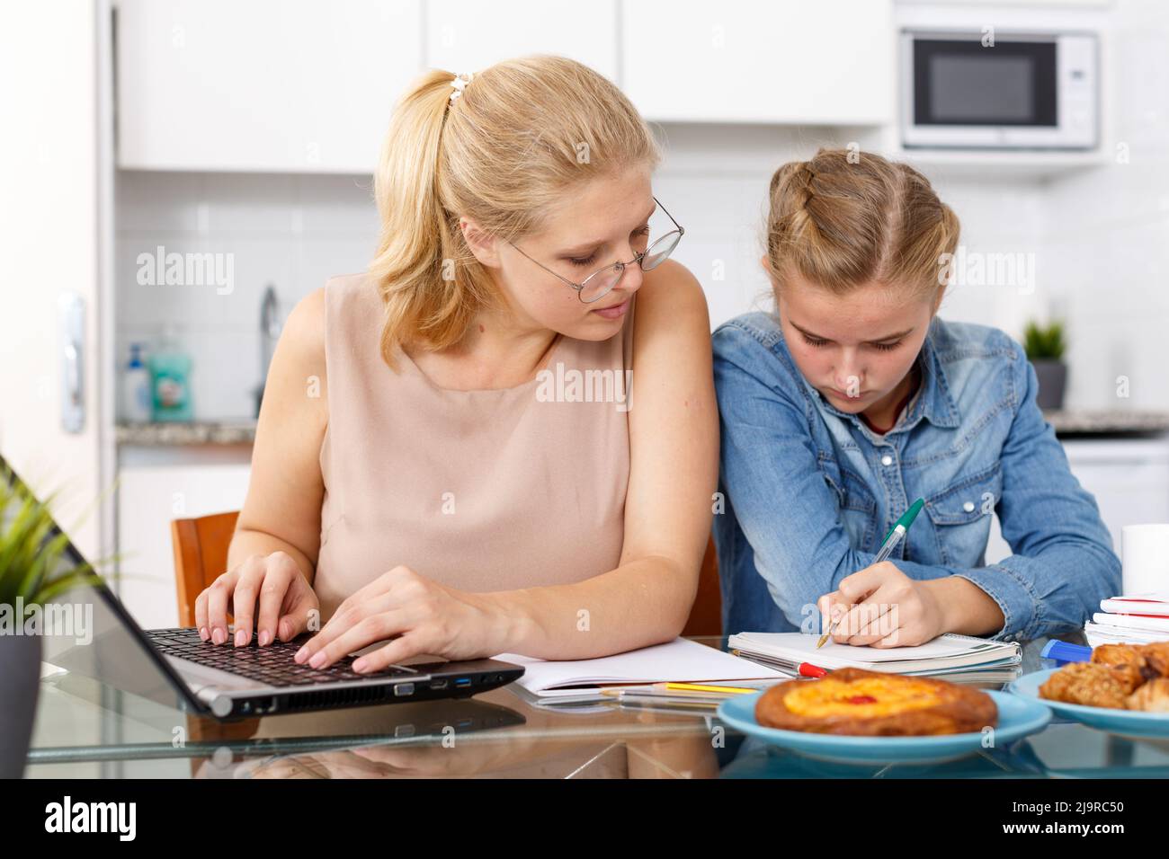 Frau hilft Tochter Hausaufgaben zu machen Stockfoto