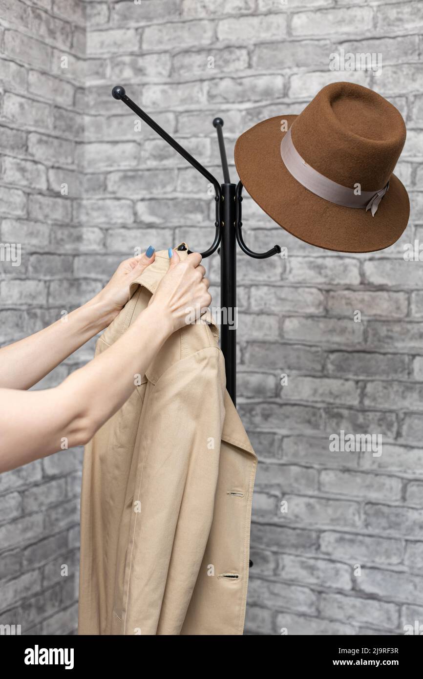 Eine Frau hängt einen Regenmantel an einen Haken an einem Kleiderbügel. Hochwertige Fotos Stockfoto