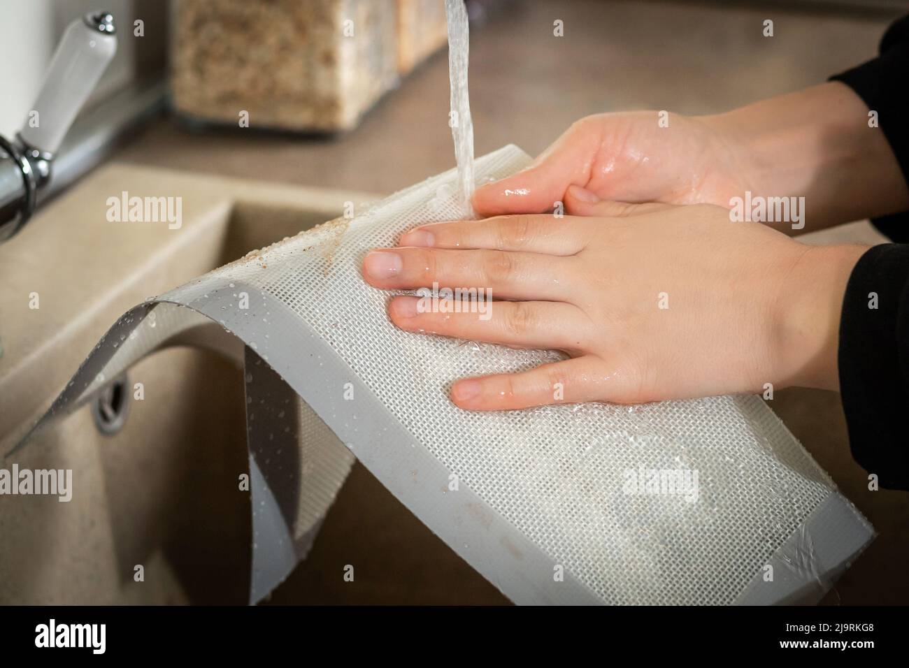 Die Silikon-Backmatte in der Küche lässt sich nach dem Kochen leicht in kaltem Wasser reinigen. Selektiver Weichfokus Stockfoto
