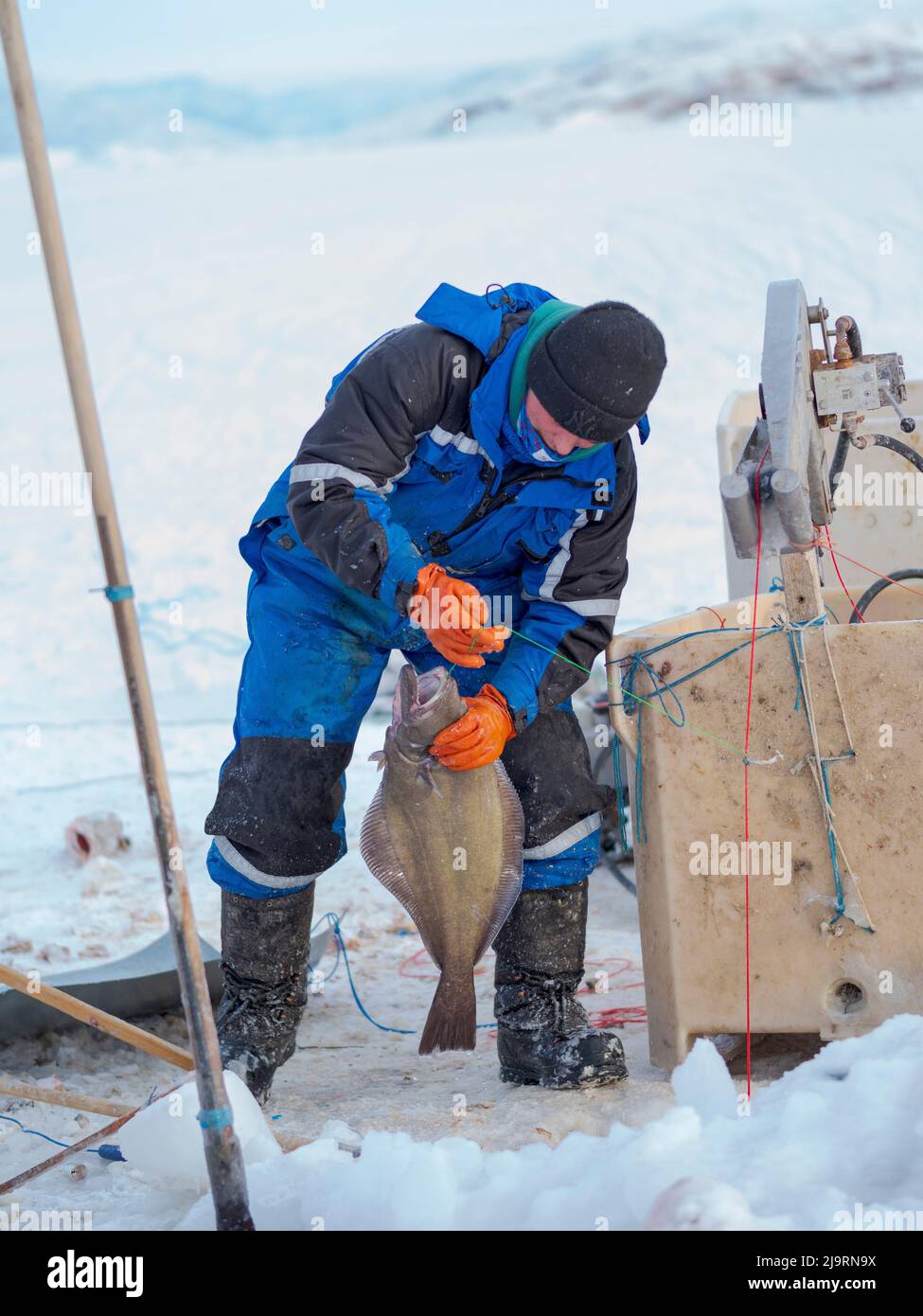 Fischer auf dem Meereis eines Fjords mit einer langen Linie. Fischerei im Winter in der Nähe von Uummannaq im nördlichen Westgrönland jenseits des Polarkreises. Grenl Stockfoto